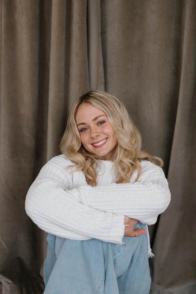 Danica Moore portrait in white chunky sweater, seated with arms crossed smiling — Free Spirit Chiropractic of Tulsa, Oklahoma