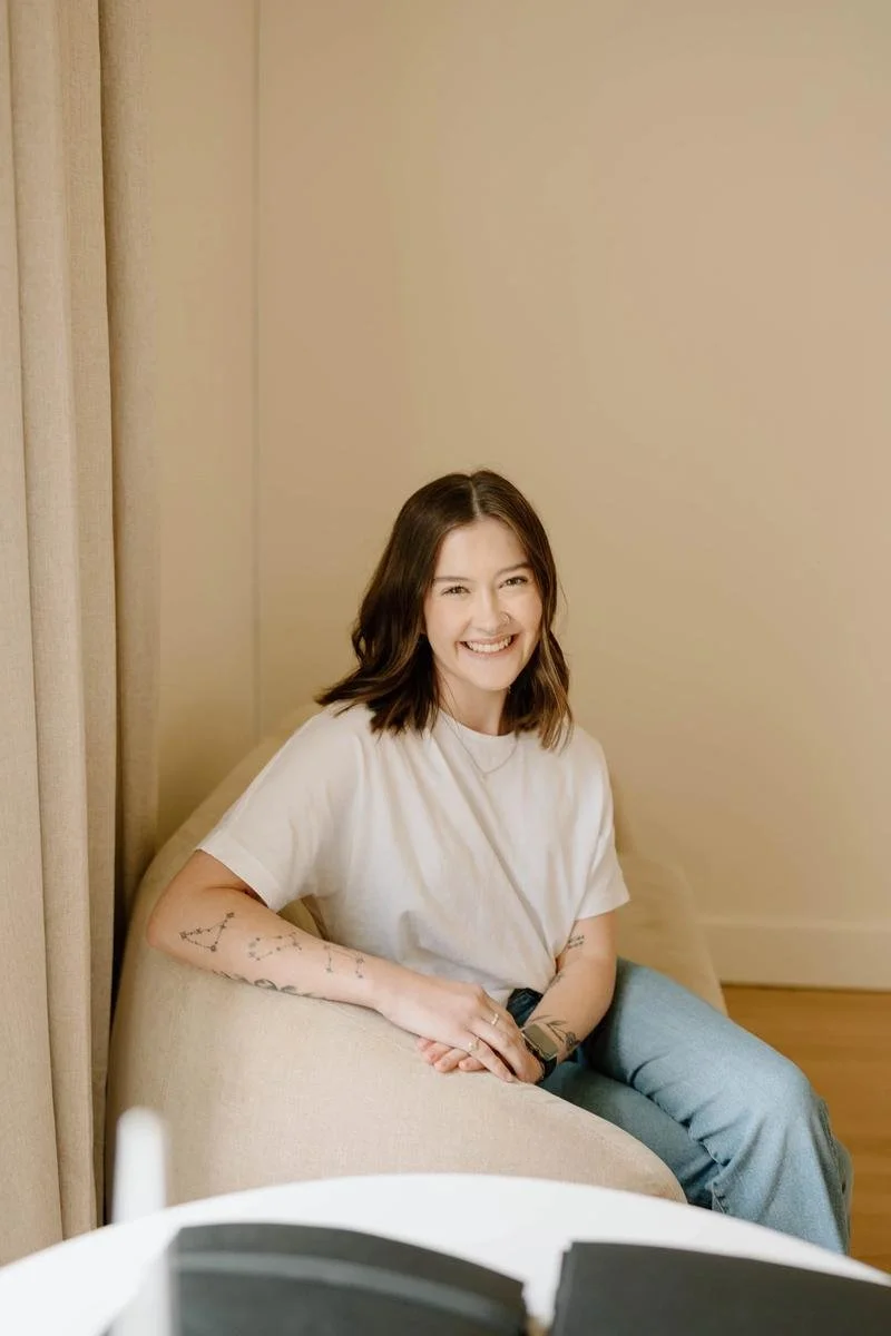Karlie Deshazo portrait in cream t-shirt seated in neutral armchair — Free Spirit Chiropractic of Tulsa, Oklahoma