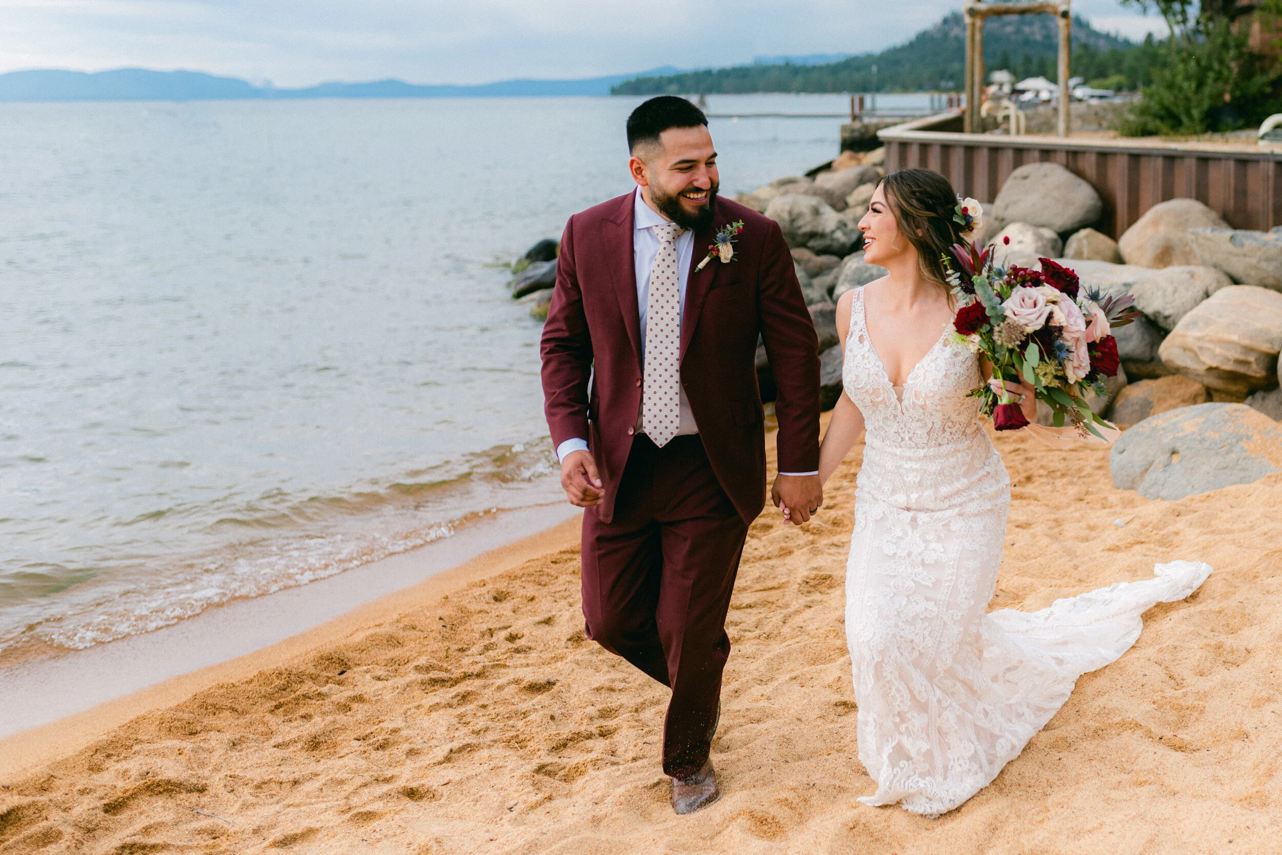 Couple smiling and holding hands as they walk on the beach after their elopement