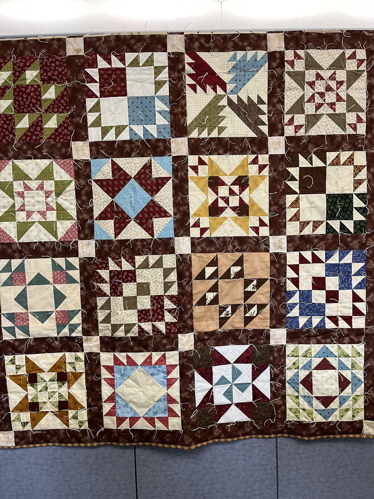 Sampler Quilt, Comforter, Twin, 60x75: Salem Mennonite Women, Salem Mennonite Church, Shickley

Quilt top is a sampler made in brown blues and greens. It was purchased at the Kansas Relief Sale. And tied to complete it.