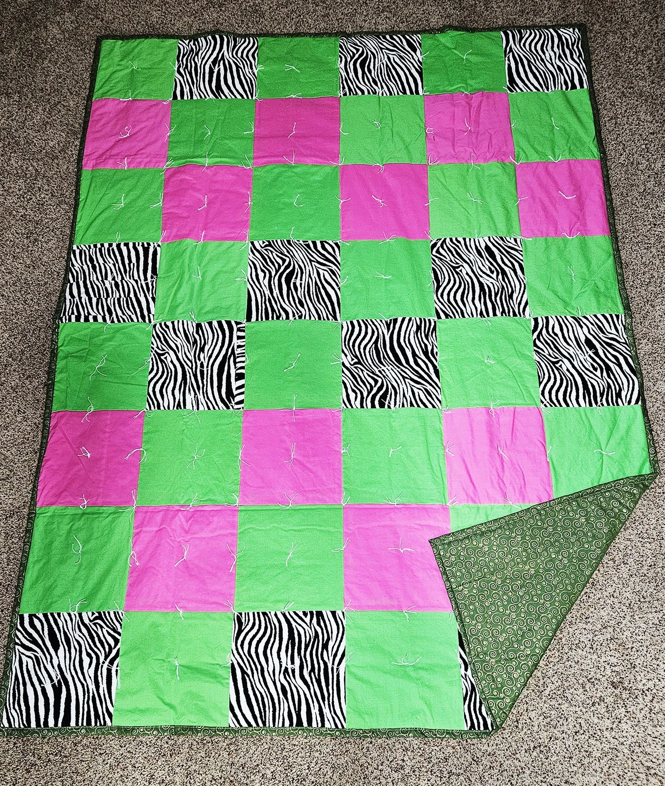 Wild Zebra, Comforter, Lap/Throw, 60x80: Bethesda Women's Ministries, Bethesda Mennonite Church

This comforter features 10" patchwork squares of hot pink, neon green, and Zebra prints.  The backing is green with gold swirls.  It was pieced, tied and