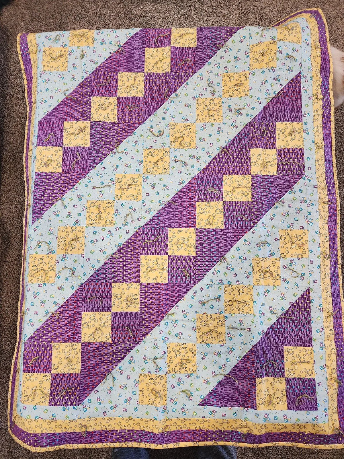 Jacob's Ladder, Quilt, Baby, 44x57: First Mennonite Church, Beatrice

Jacobs Ladder Baby Quilt in shades of yellow, purple and blue with a yellow backing.