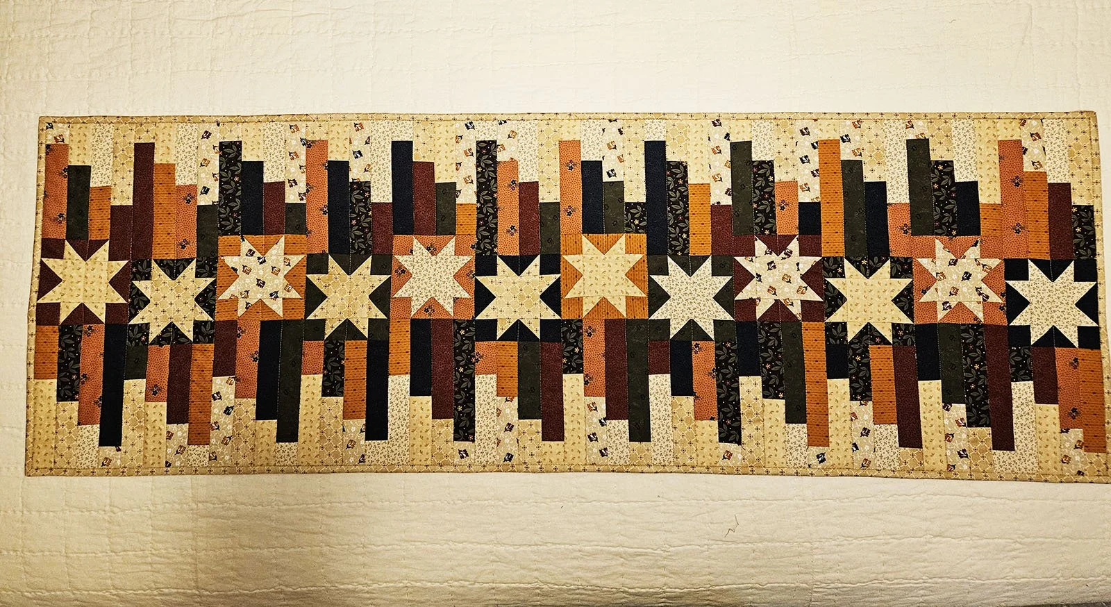 Weybridge Table Runner, 16x48: Joy Steckley, Bethesda Mennonite Church

This table runner features fabric from the Color Challenge in navy blue, green, burgundy, gold and cream.  Rows of stars are accompanied by contrasting light and dark patchwork s