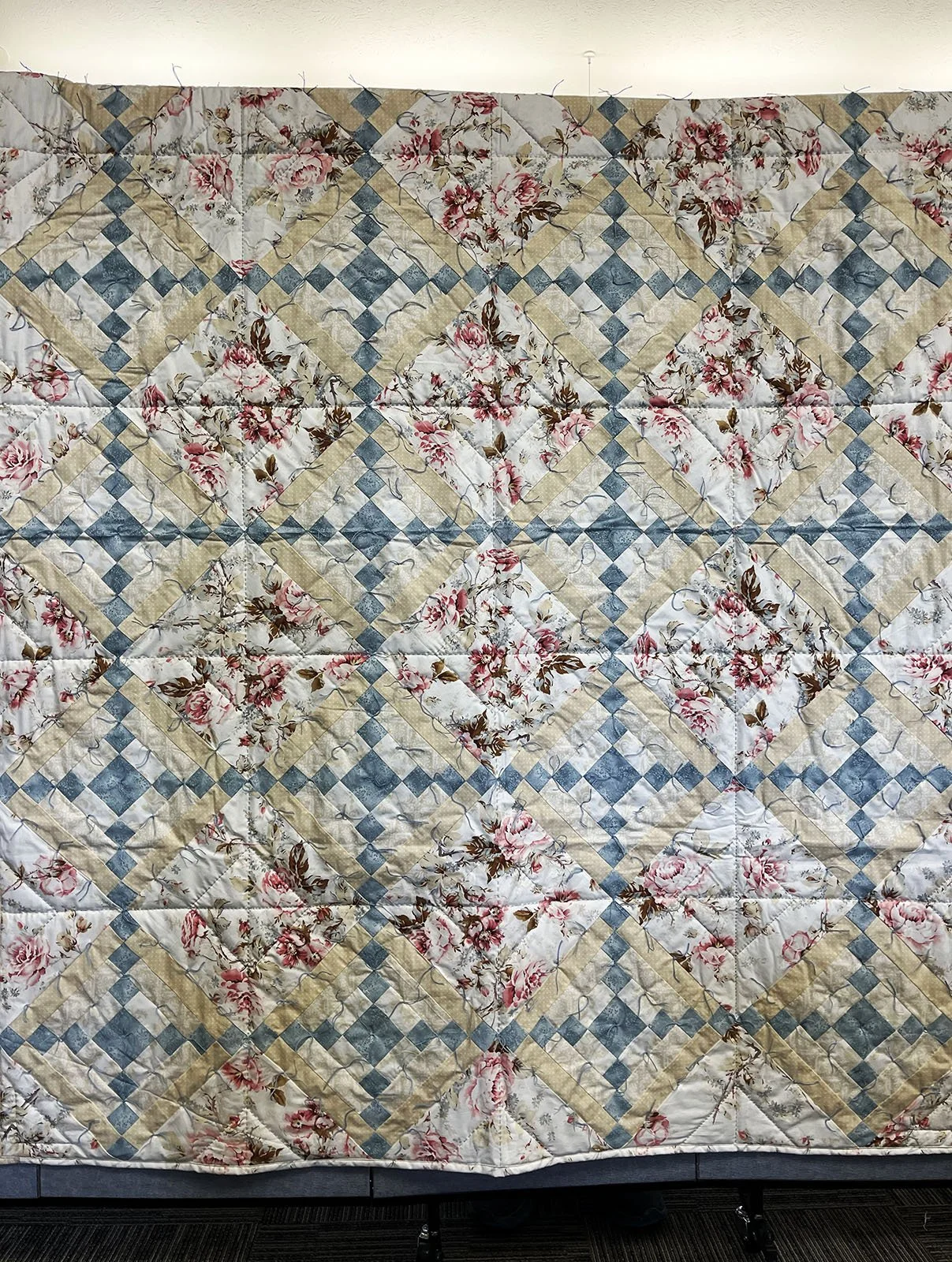 Springtime Quilt, Full, 66x77: Salem Mennonite Women, Salem Mennonite, Shickley

Quilt top purchased at the Kansas Relief Sale, floral fabric squares and Courthouse steps blocks. Color blue,pink and tan. Stitched and tied.