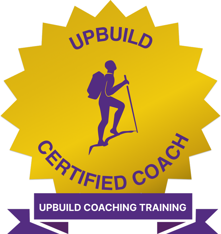 A badge with a yellow starburst background featuring a purple silhouette of a person with a backpack and hiking pole. The text reads 'UPBUILD CERTIFIED COACH' at the top and 'UPBUILD COACHING TRAINING' on a purple ribbon at the bottom.