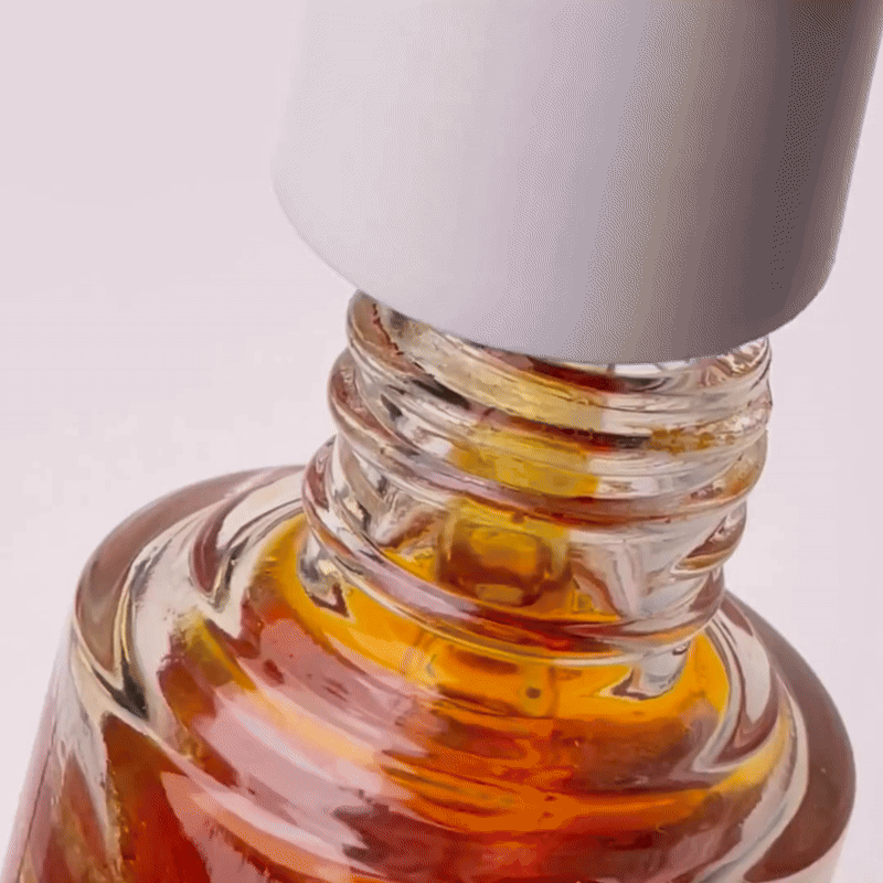 A cosmetic dropper coming out of a bottle and dripping orange serum