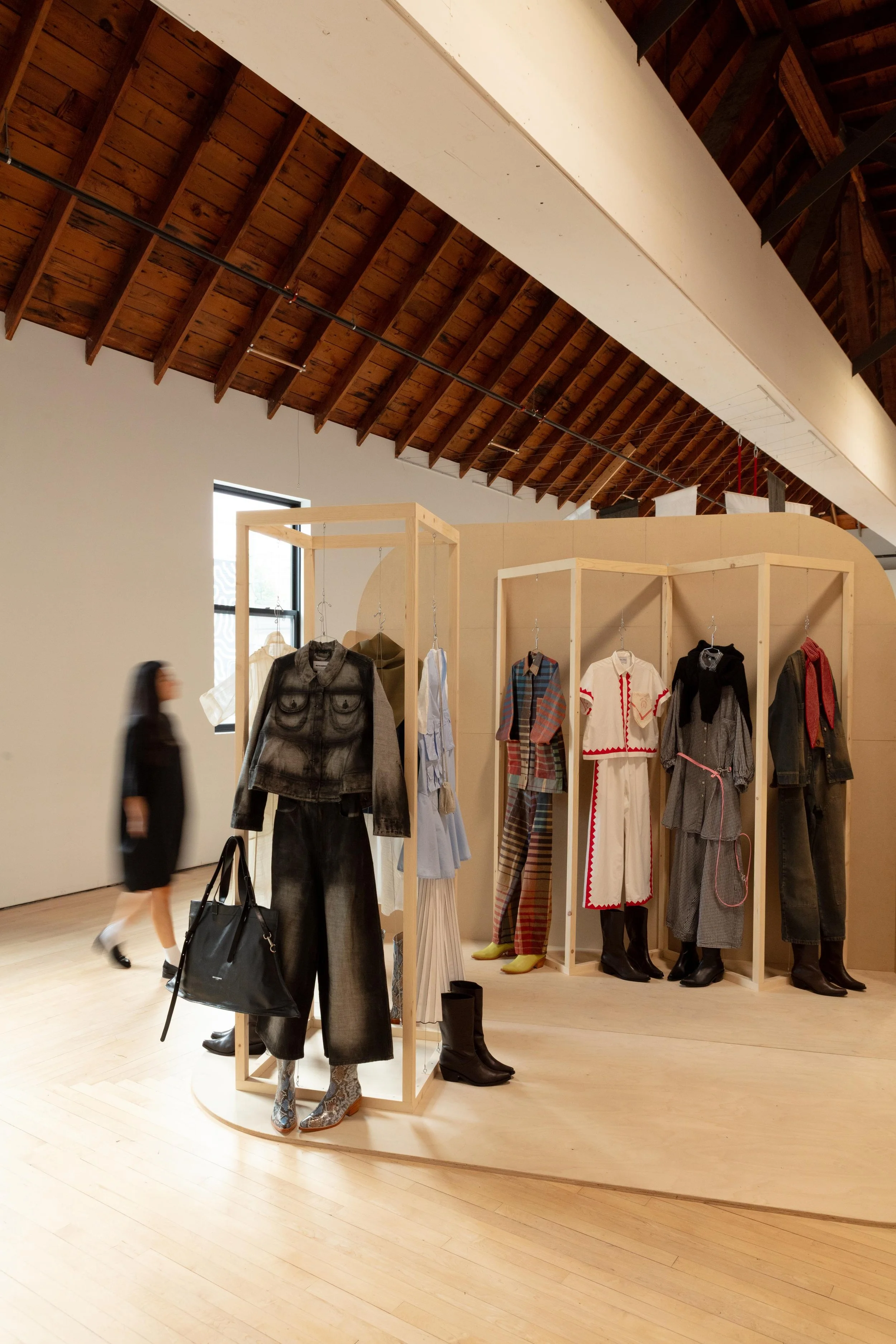 Curated clothing display in a modern showroom with hanging garments on wooden fixtures