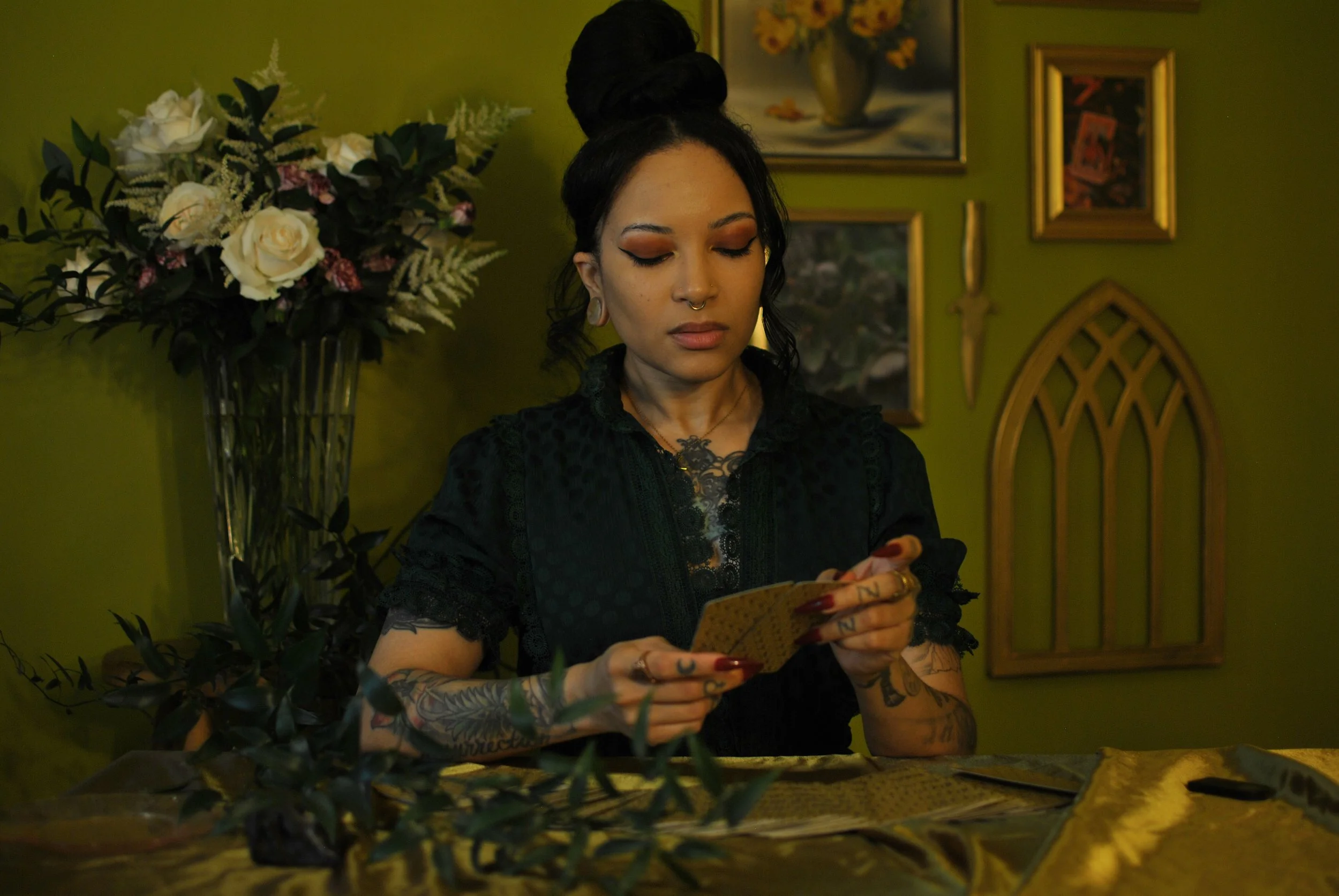a self-portrait of me reading tarot. vintage green dress and tattoos are visible. i use tarot as a personal wellness tool and to help others find creative clarity and self-trust.