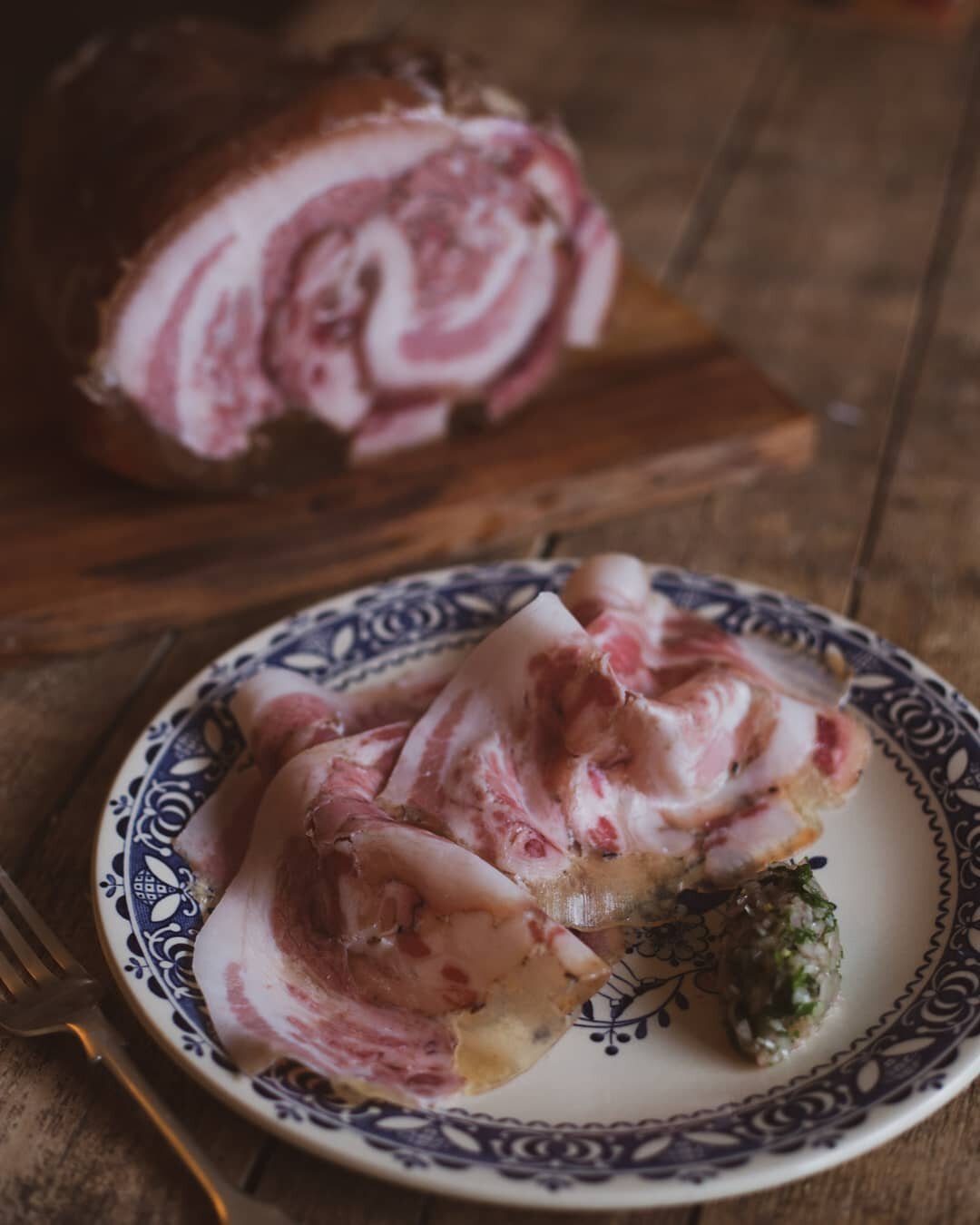 Porchetta di Testa with vinegered shallots and parsley.

A quintessential Italian peasant preparation of a fresh pig's head. The heads of our British Lops have been deboned, cured in salt and spices before being tightly rolled, tied and cooked very g