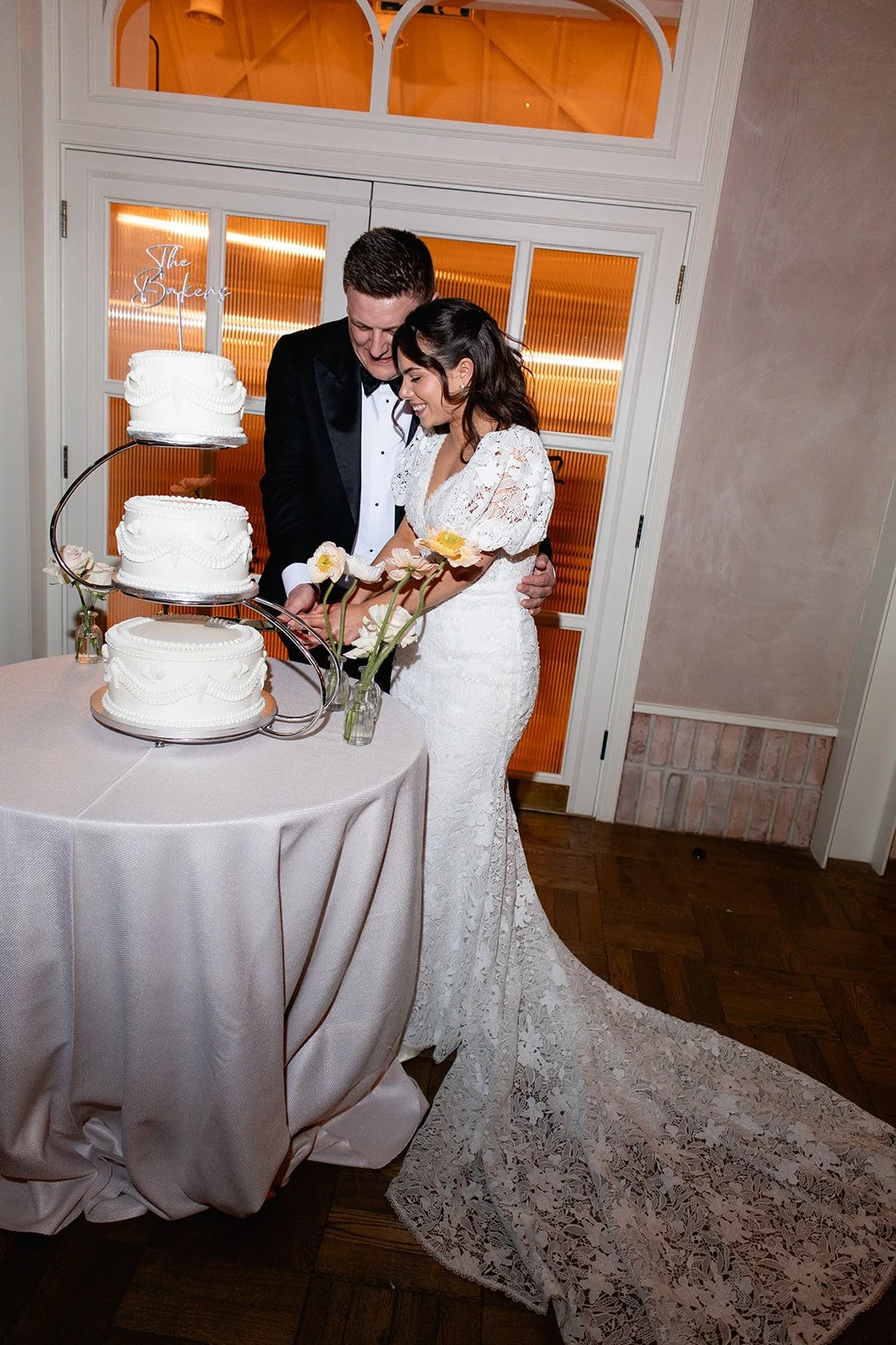 A bride and groom cut a wedding cake together at their wedding reception.