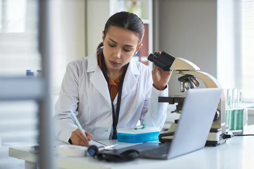 Científica trabajando con microscopio en laboratorio
