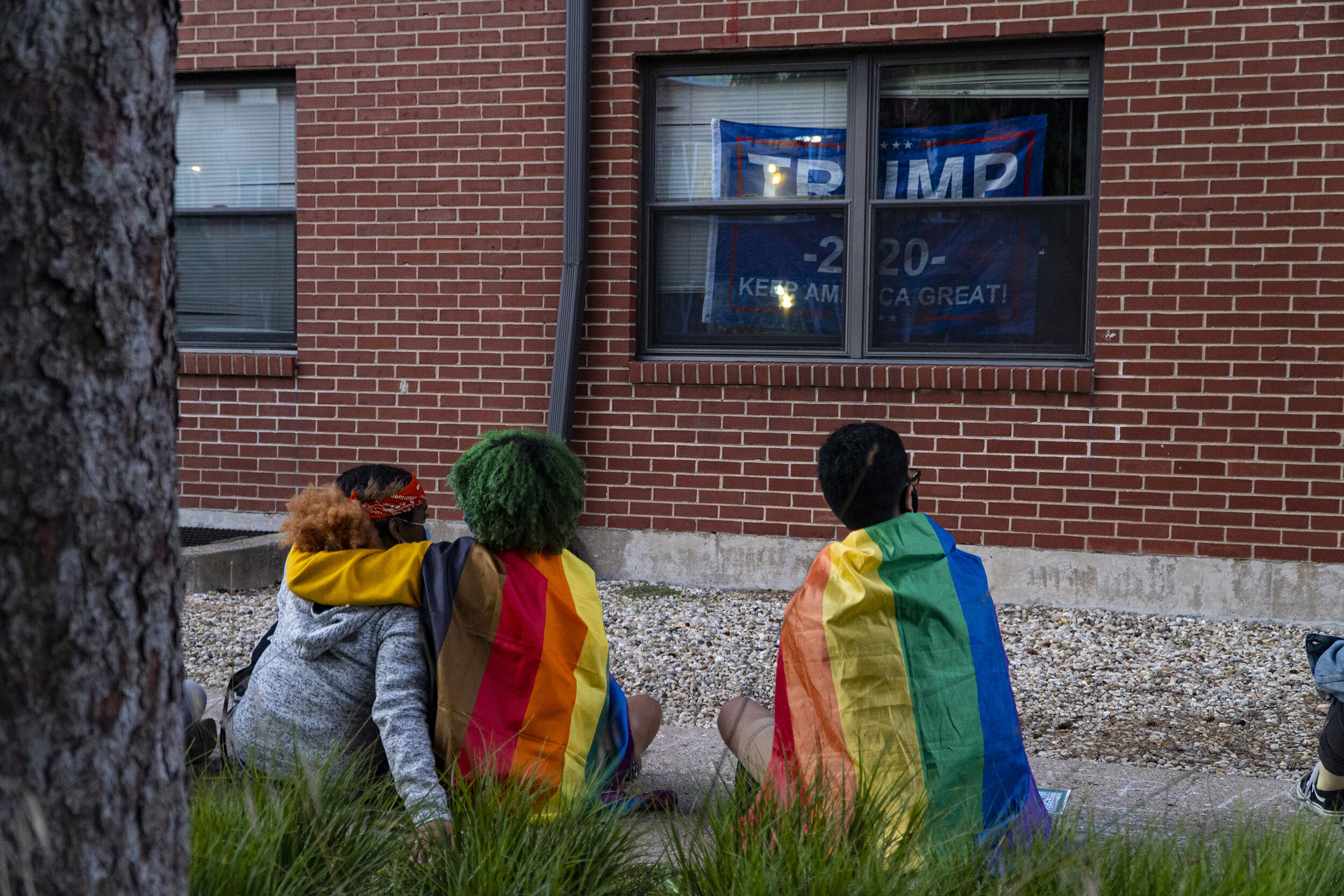  Students wrapped in pride flags outside the window with hanging Trump 2020 flags. (Rob Nguyen/TKS) 