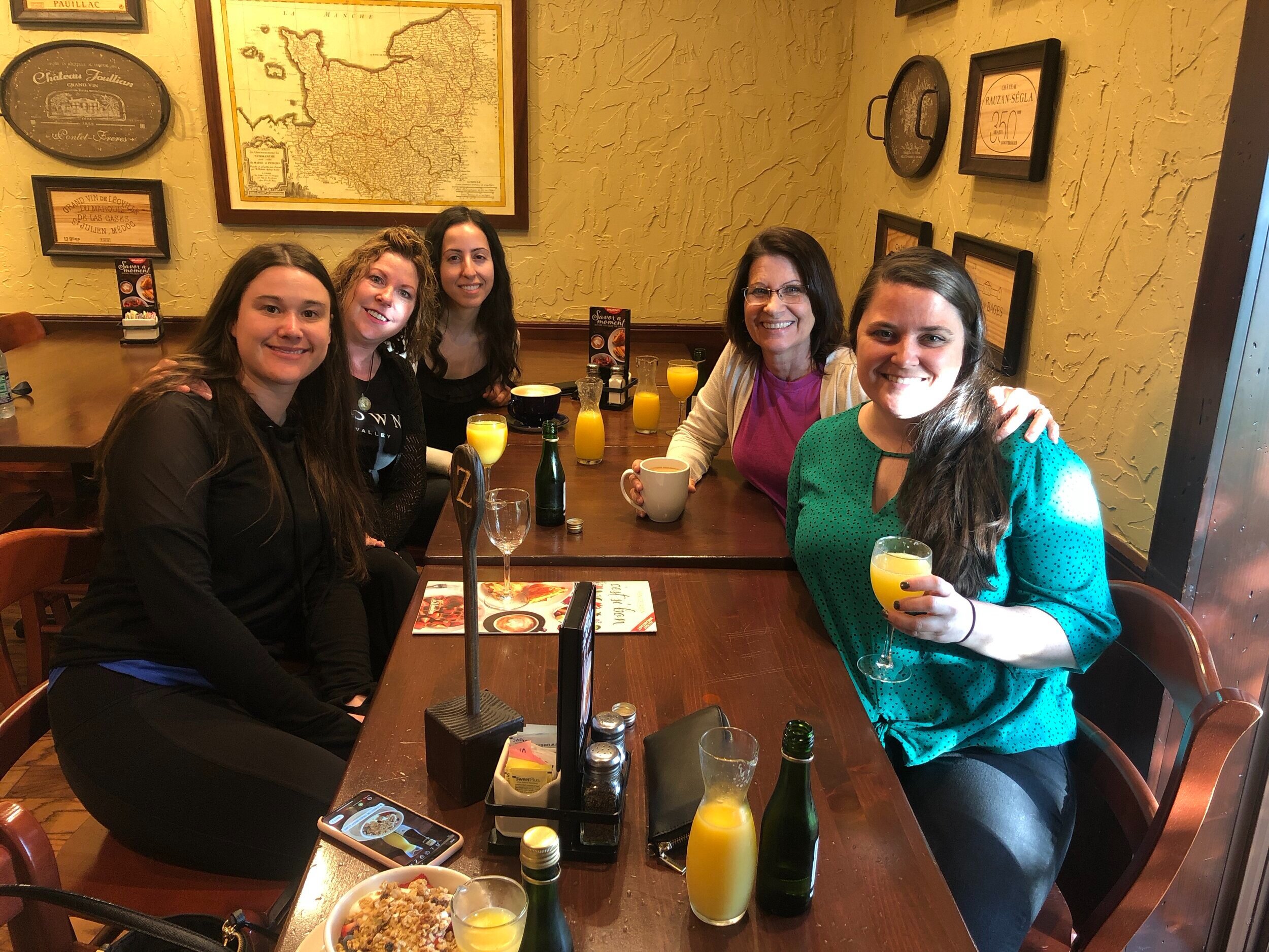 group of women enjoying mimosas and brunch during a girls day out on a girls trip vacation at at La Madeleine restaurant  in Orlando Florida