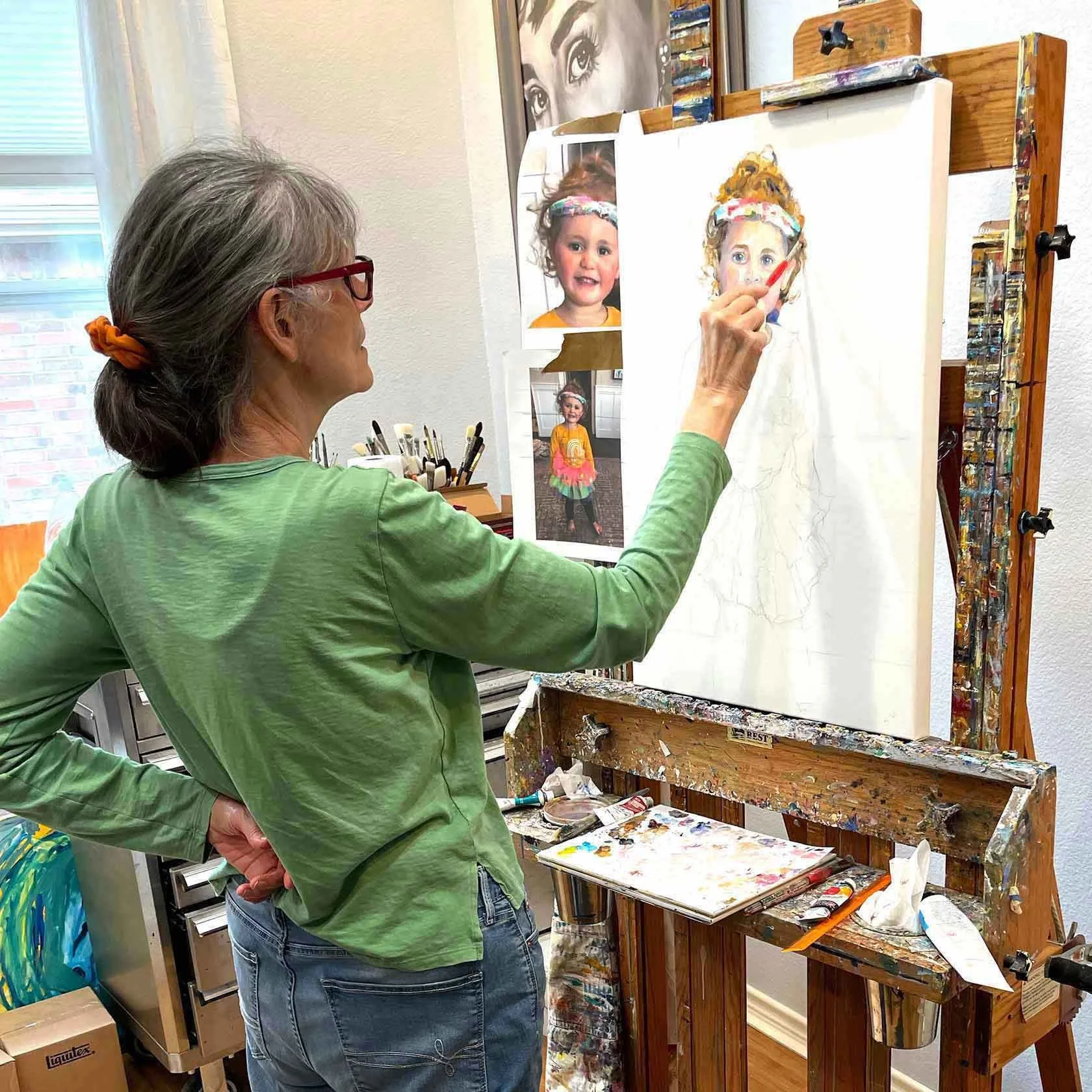 Laurie Pace in studio painting a portrait of a 3 yr old girl