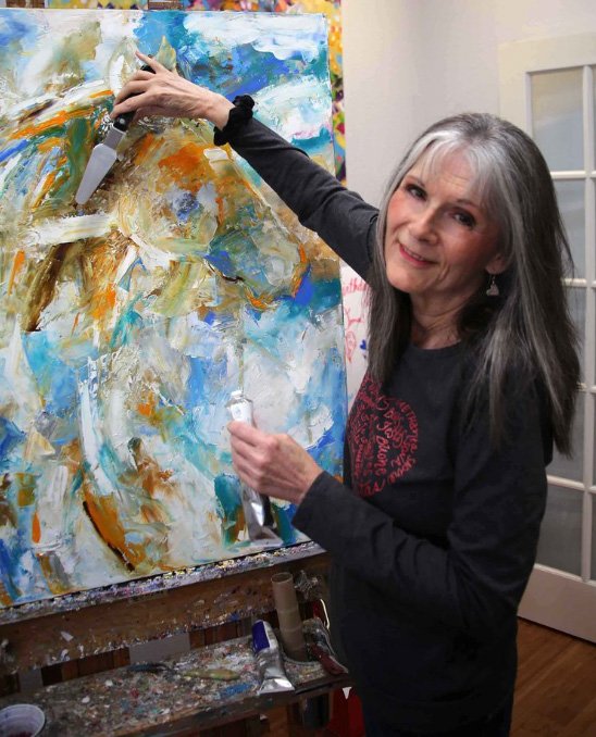 Laurie Pace in Studio working on large horse painting with blues and white and orange