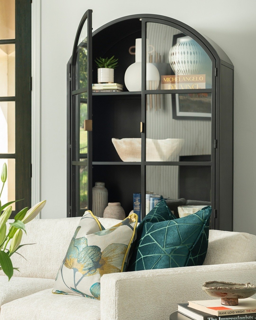 CLOSE UP DETAILS // A closer look at the living room cabinetry reveals thoughtful craftsmanship and elegant styling.😌

The custom pillows and sofa peek softly from behind the arched iron and glass cabinet, which stands as a striking focal point. Its