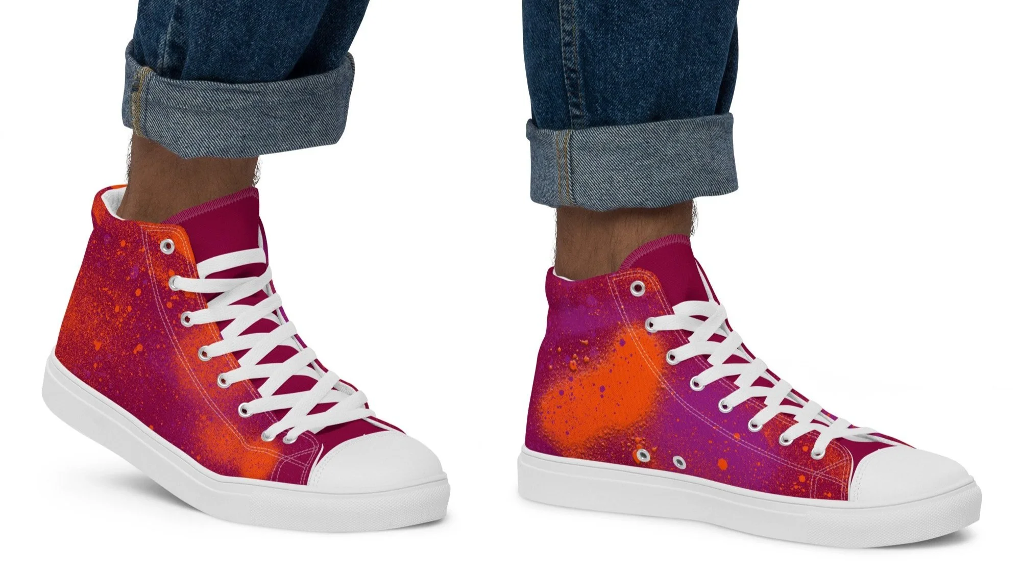 Pair of high-top sneakers with a vibrant paint splatter pattern in red, orange, purple, and pink, worn with rolled-up blue jeans.