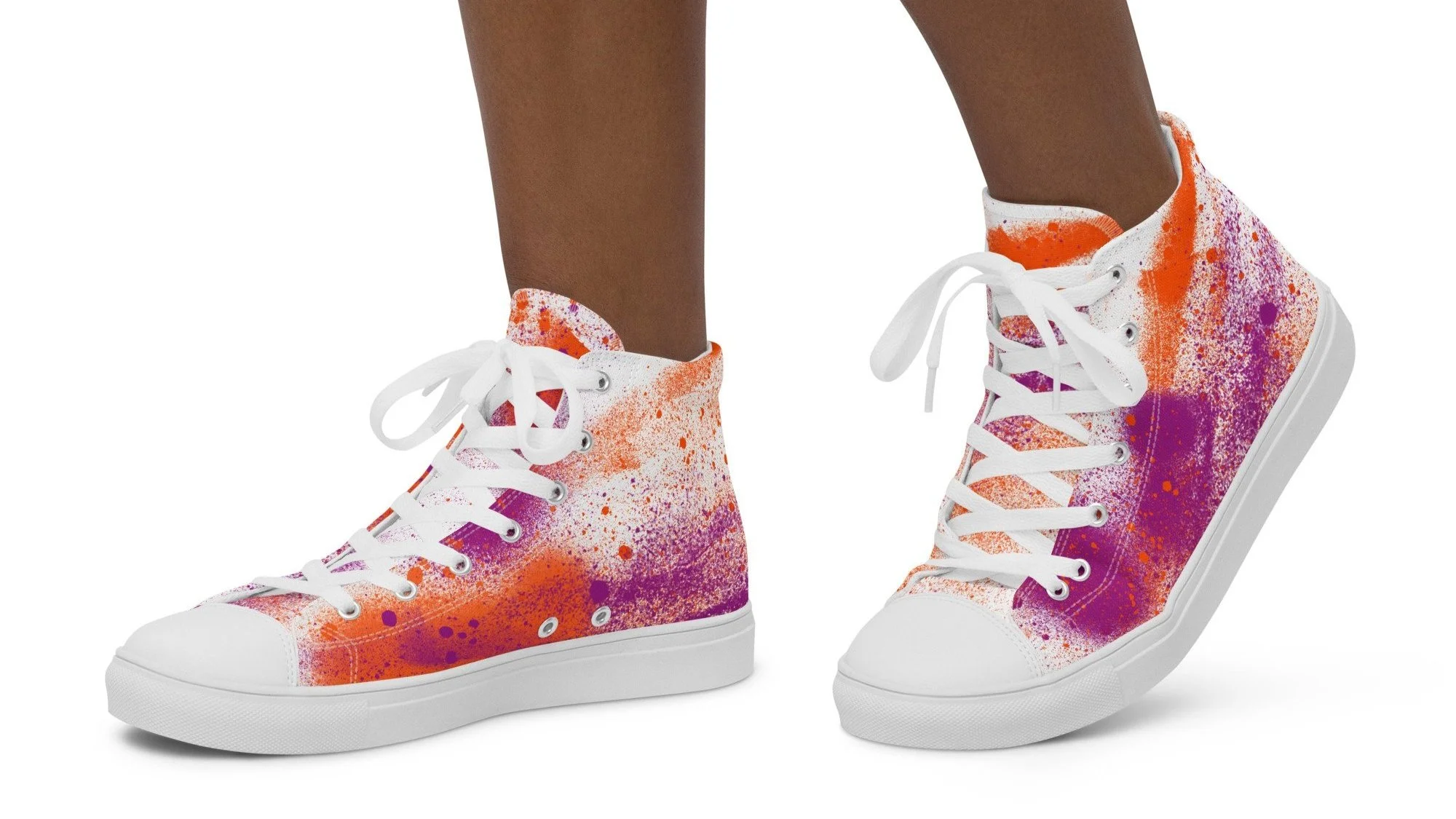 A pair of high-top sneakers with orange, purple, and white paint splatter design on the canvas, white laces, and white soles worn by a person with dark skin, pictured against a white background.
