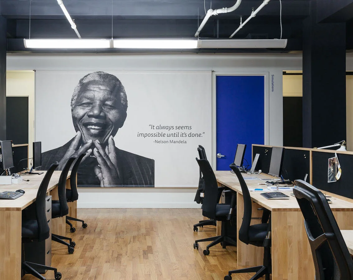 Andela NYC office interior design with custom desks, black chairs and mural