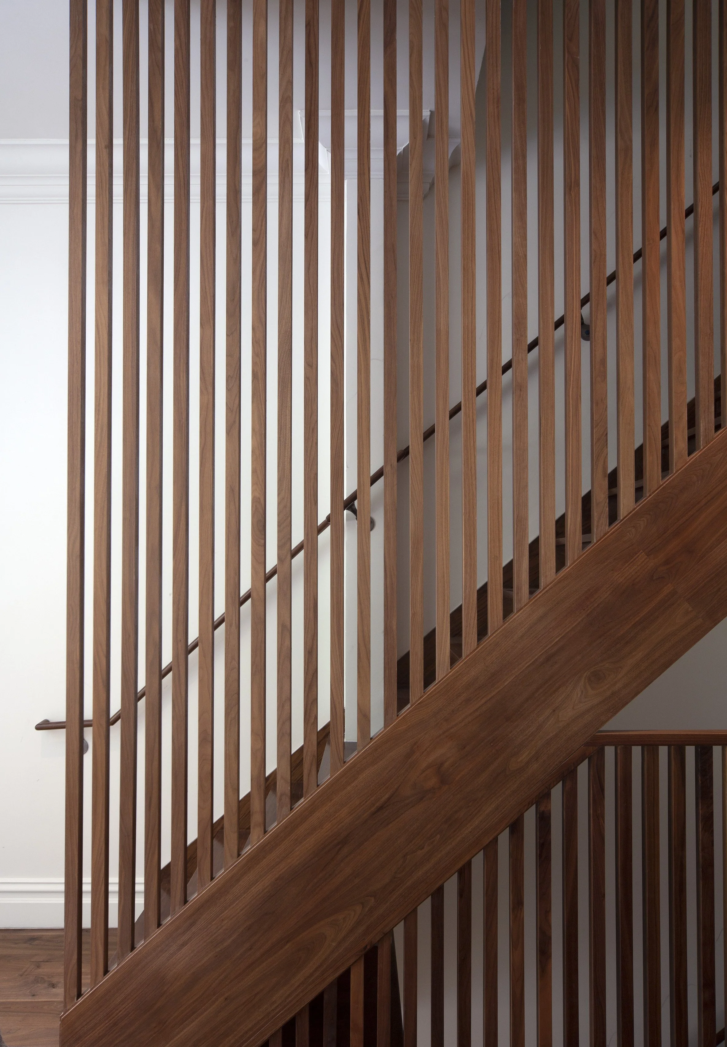 Wooden staircase with vertical slats and railing in a modern interior.