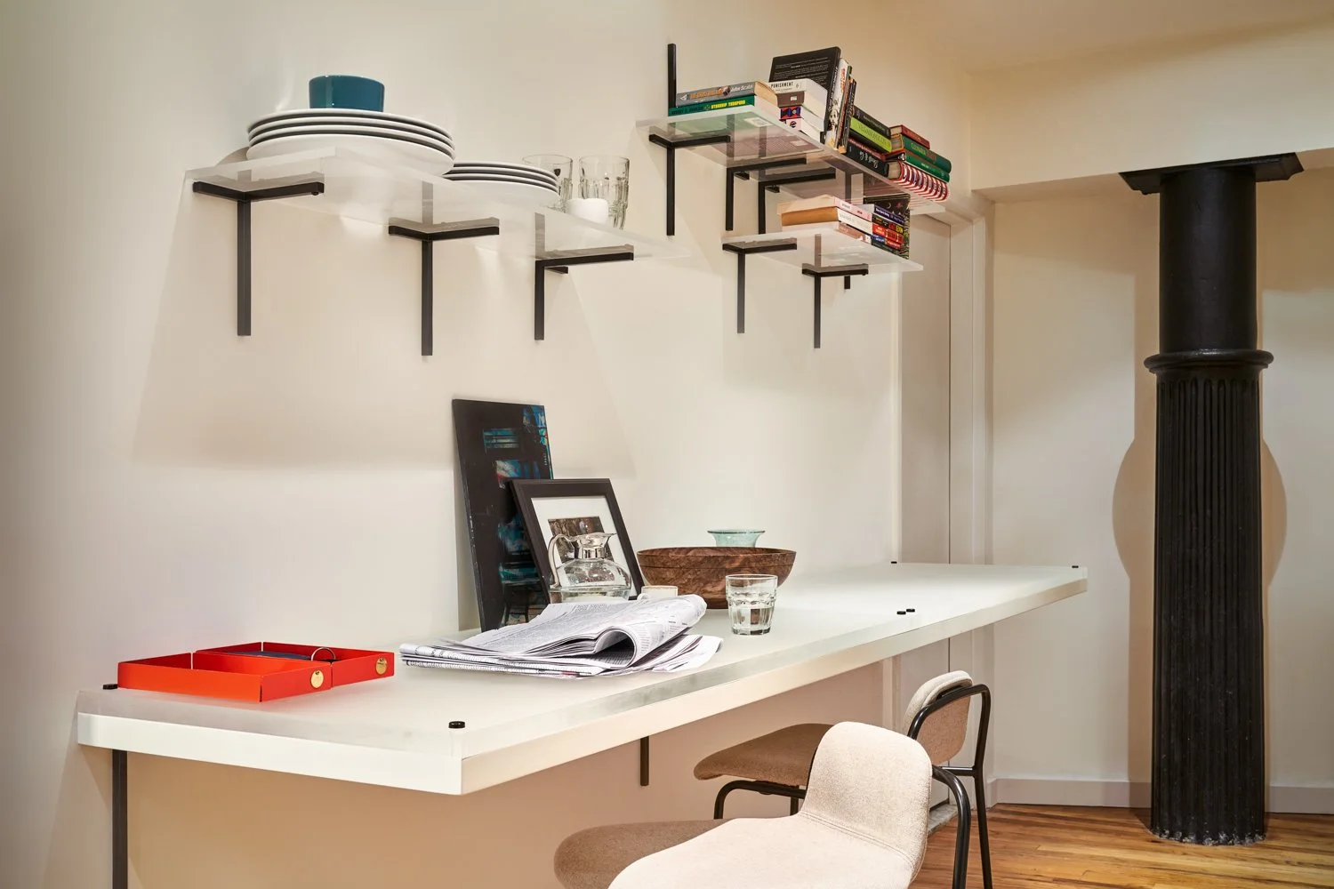 Modern workspace with a white desk, bookshelves, and two chairs, situated near a black column.