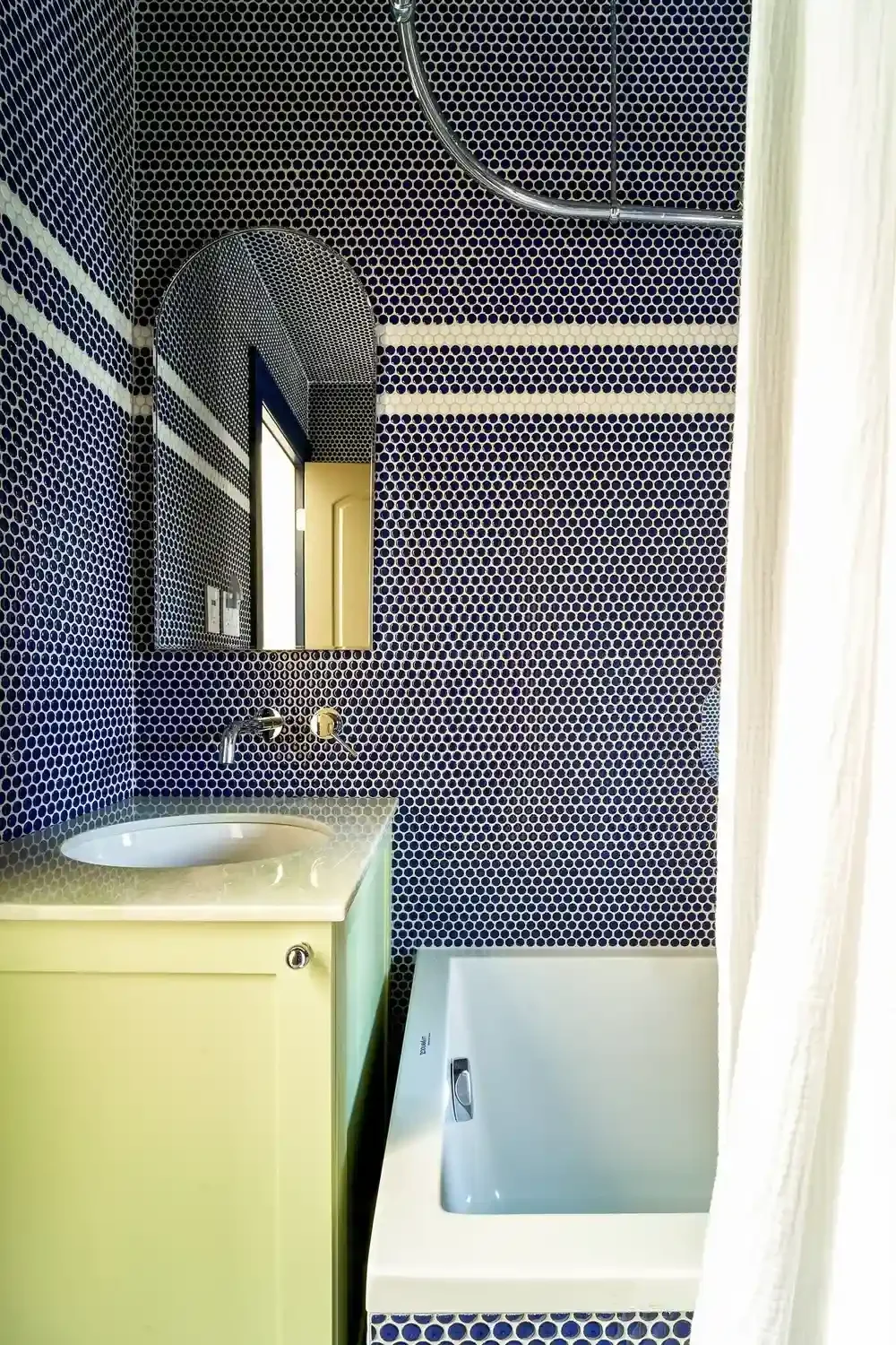 Yellow bathroom sink in blue tiled renovated bathroom