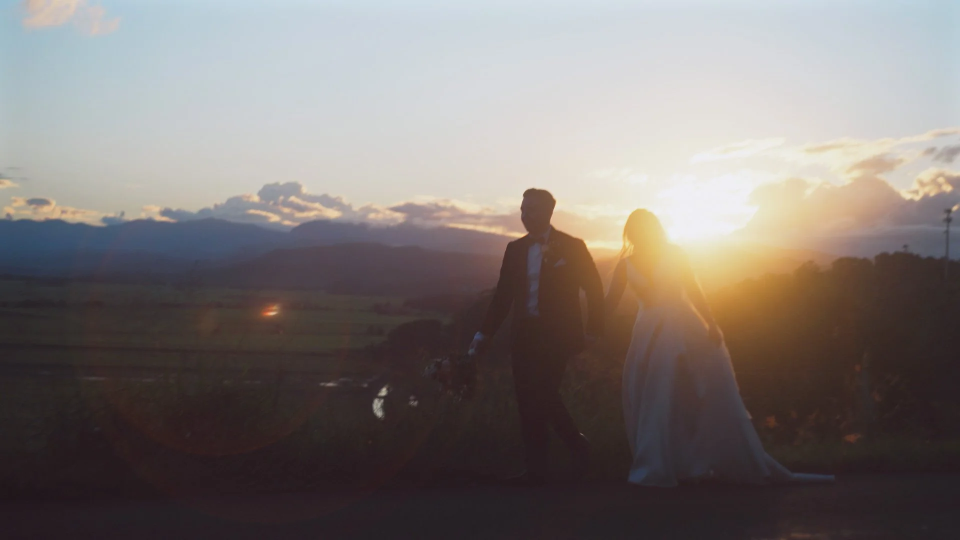 bride and groom holding hands walking in the sunset.jpg