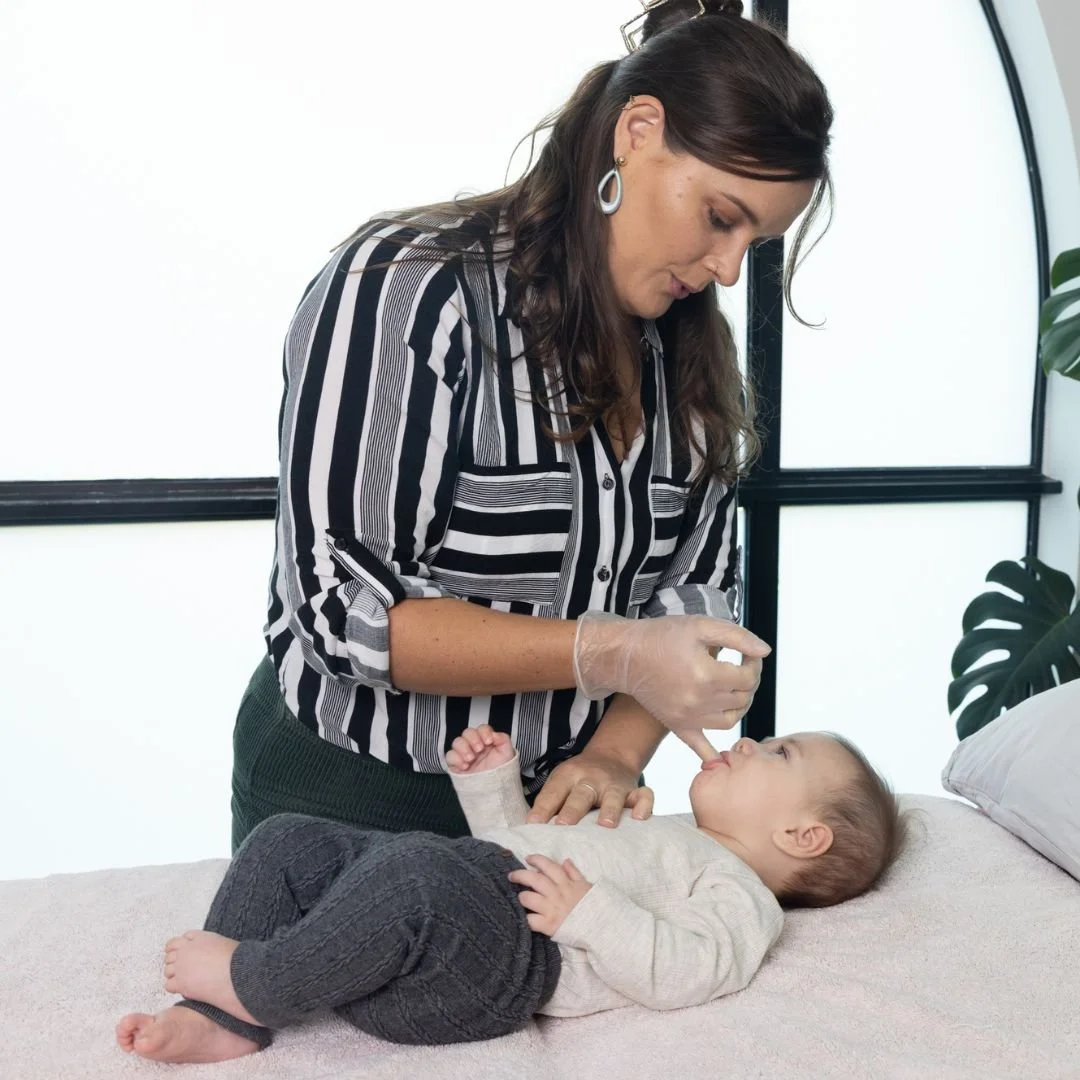 Osteopath gently assessing a newborn baby for tongue tie at Pivot Osteopathy Brisbane