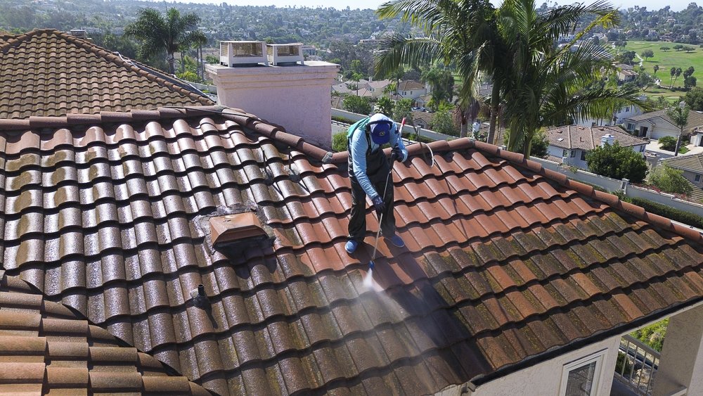 Power wash company employee cleaning a roof