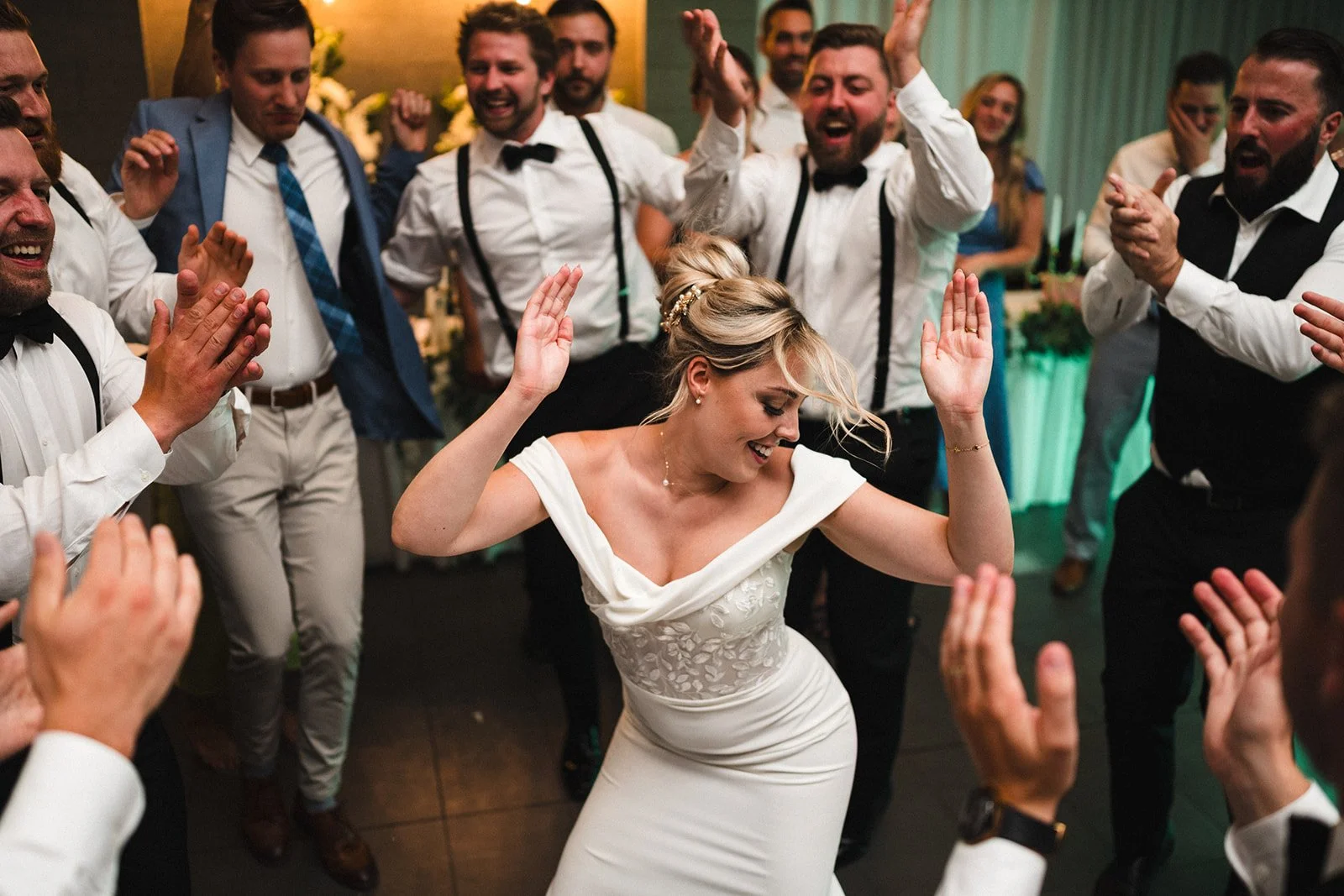 Bride dancing and smiling with guests at a wedding reception.