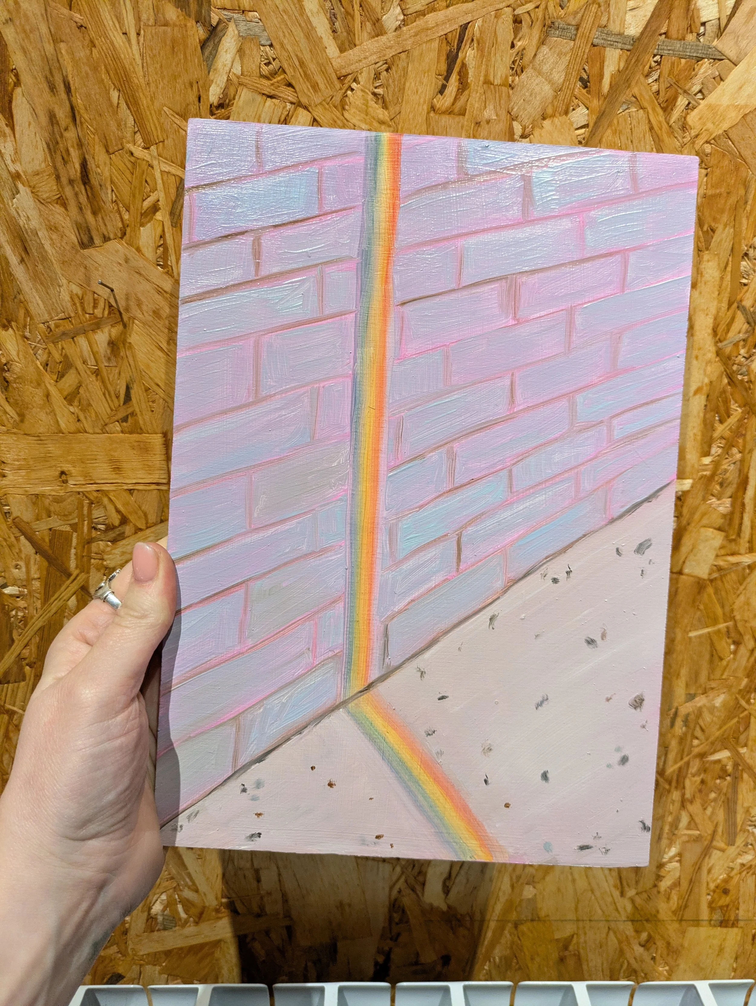 Oil painting of a rainbow in a straight line on a wall and going onto the floor.