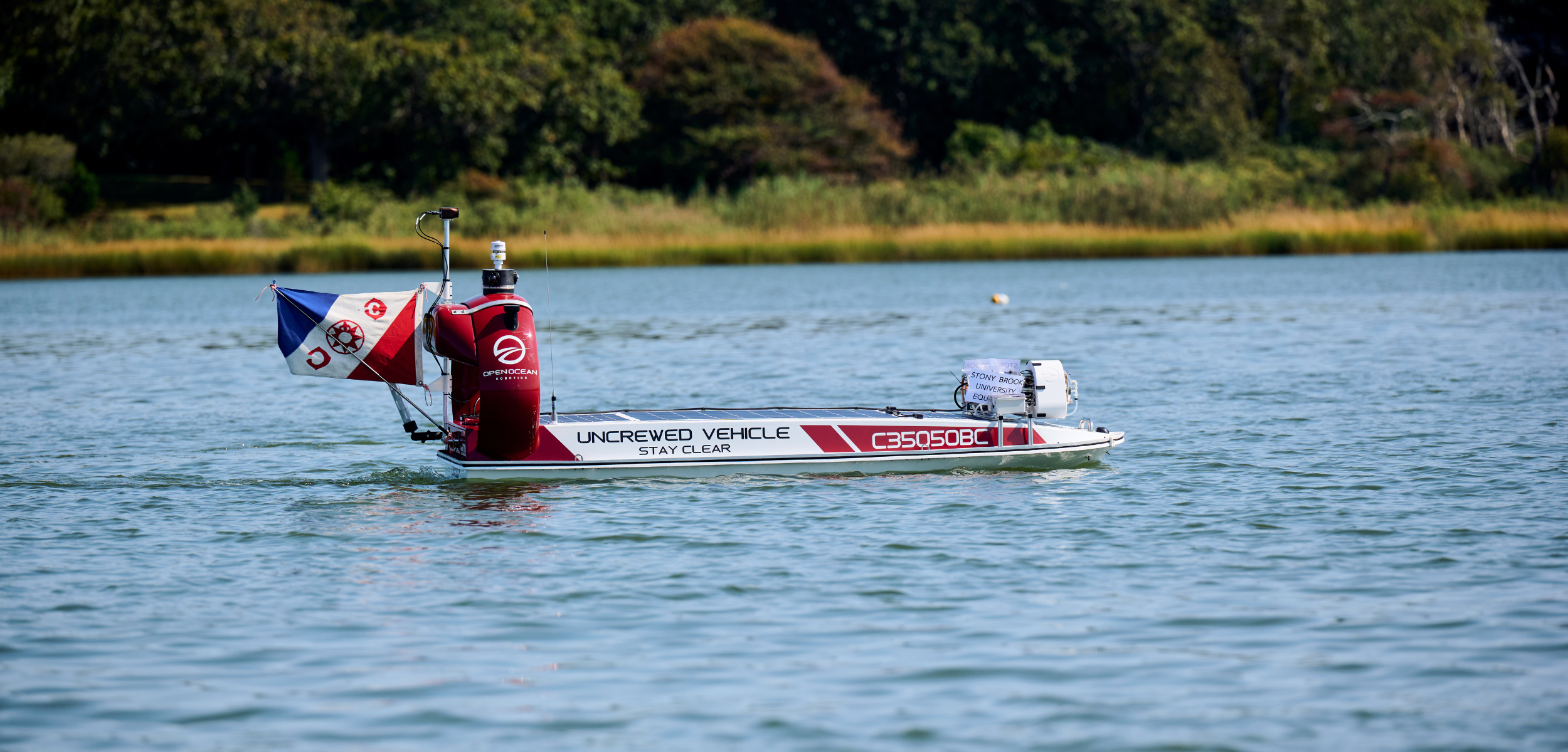 DataXplorer, a 12-foot Unscrewed Surface Vessel outfitted with an environmental DNA (eDNA) sampler. The flag denotes the Explorers Club expedition for this project. 