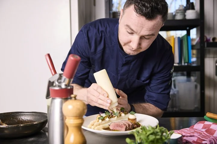 Werkportret van chef die bord opmaakt