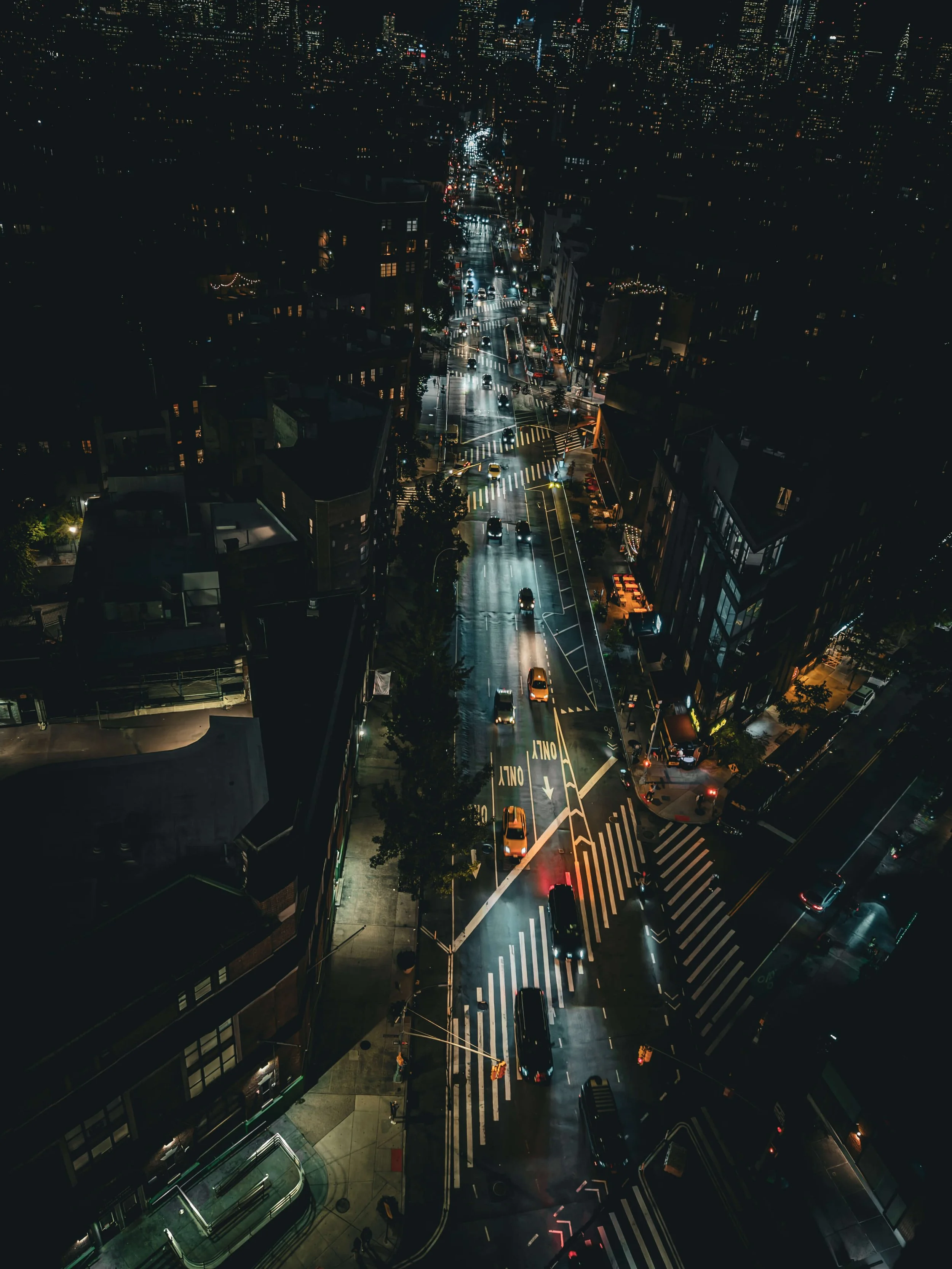 Night aerial view of a busy city intersection with cars, traffic lights, and tall buildings.