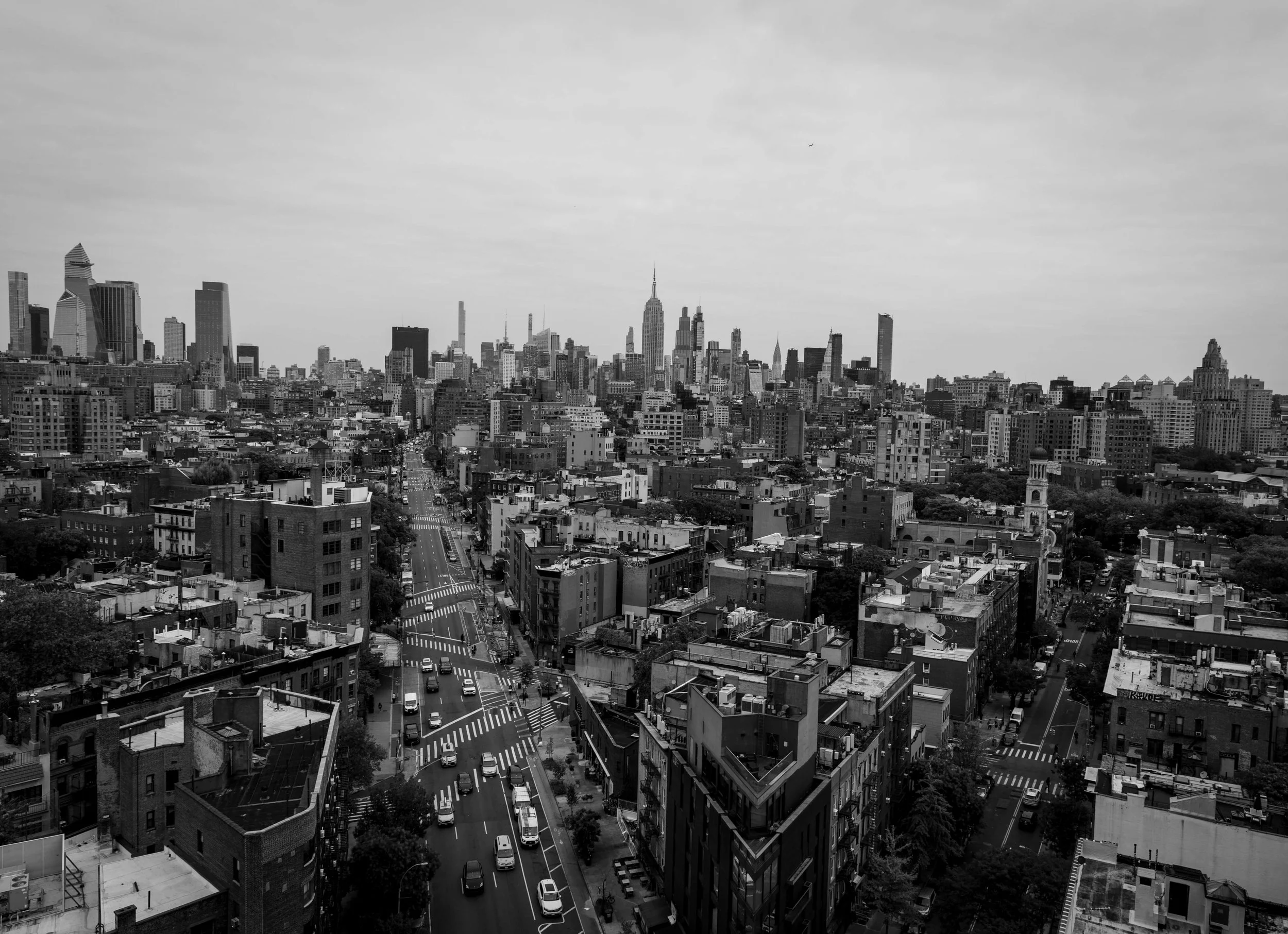 Black and white aerial view of New York City skyline with tall buildings and streets filled with cars.