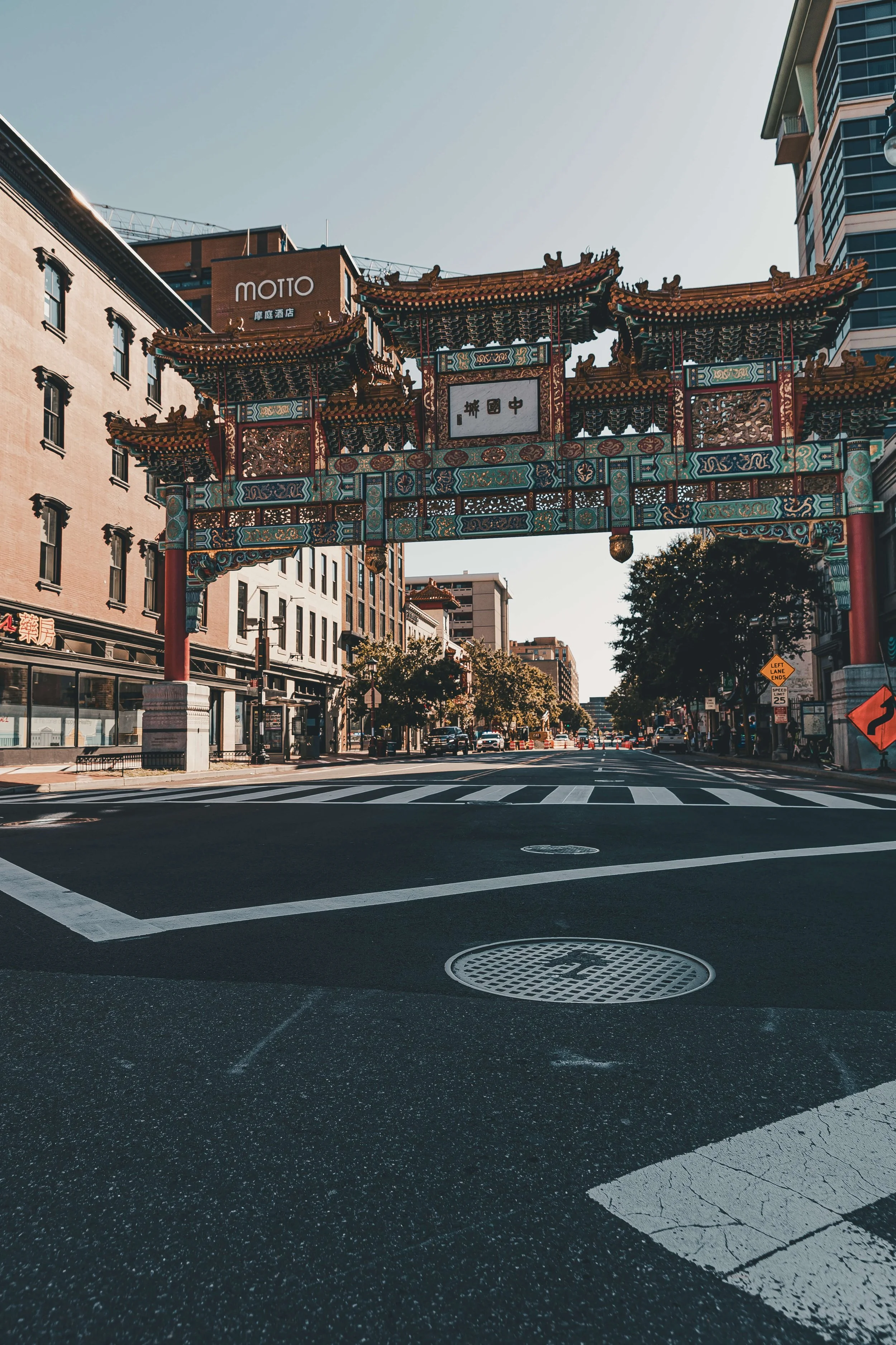 Traditional Chinese-style archway over an urban street with buildings and trees.