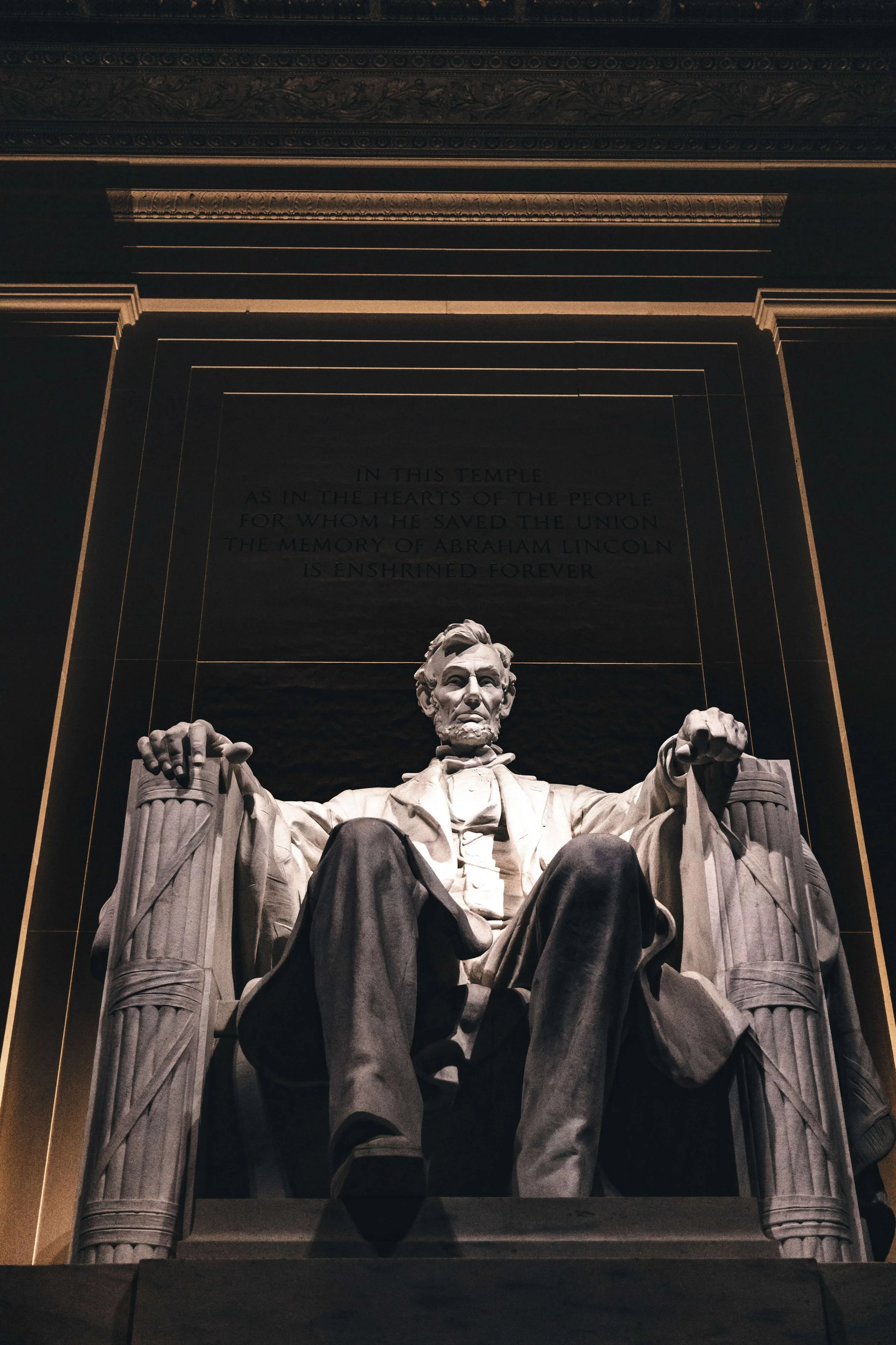 Low-angle view of the Lincoln Memorial in Washington D.C., featuring the seated statue of Abraham Lincoln made of white marble.