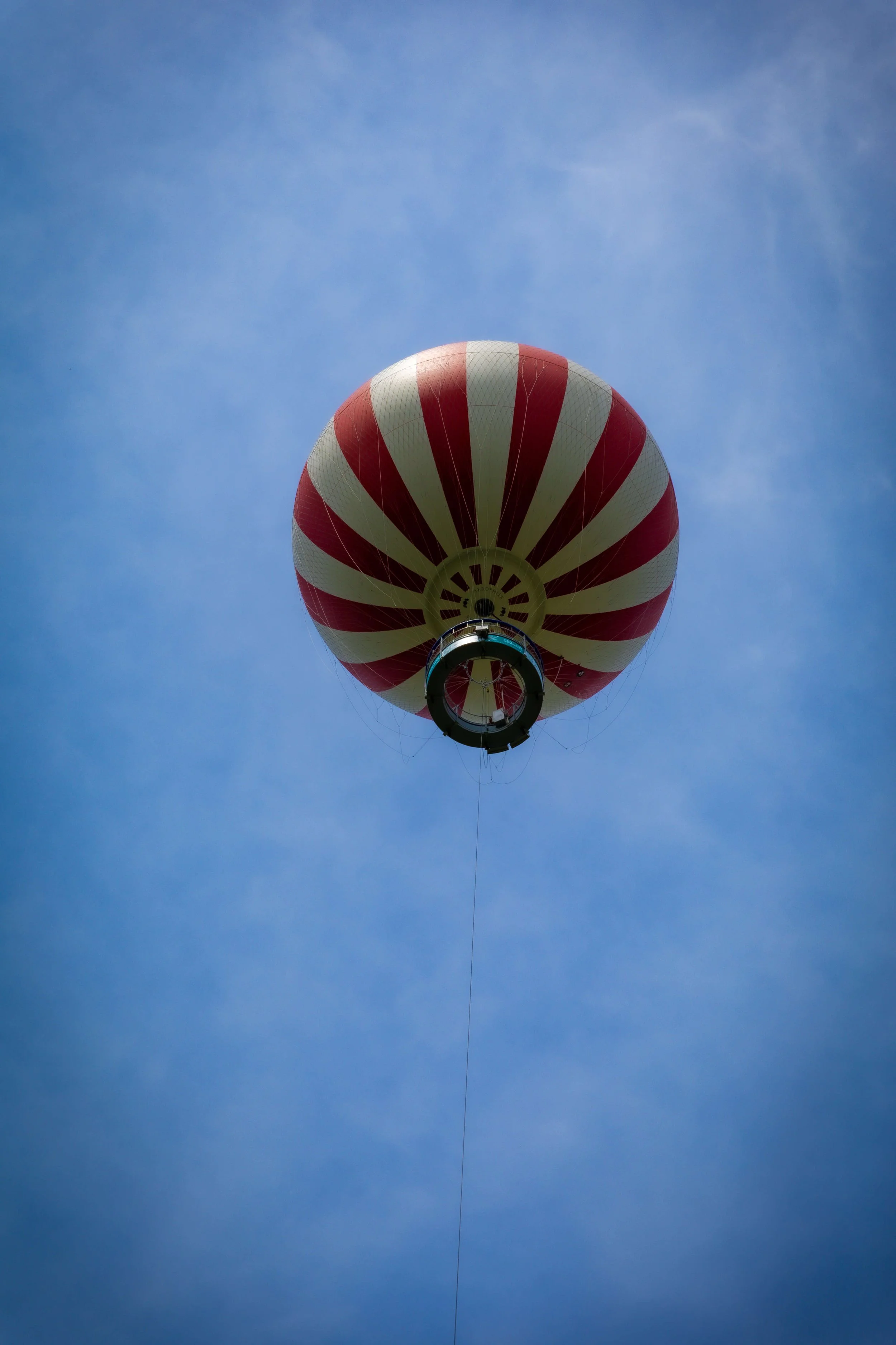 A hot air balloon with red and white stripes floating in a clear blue sky.