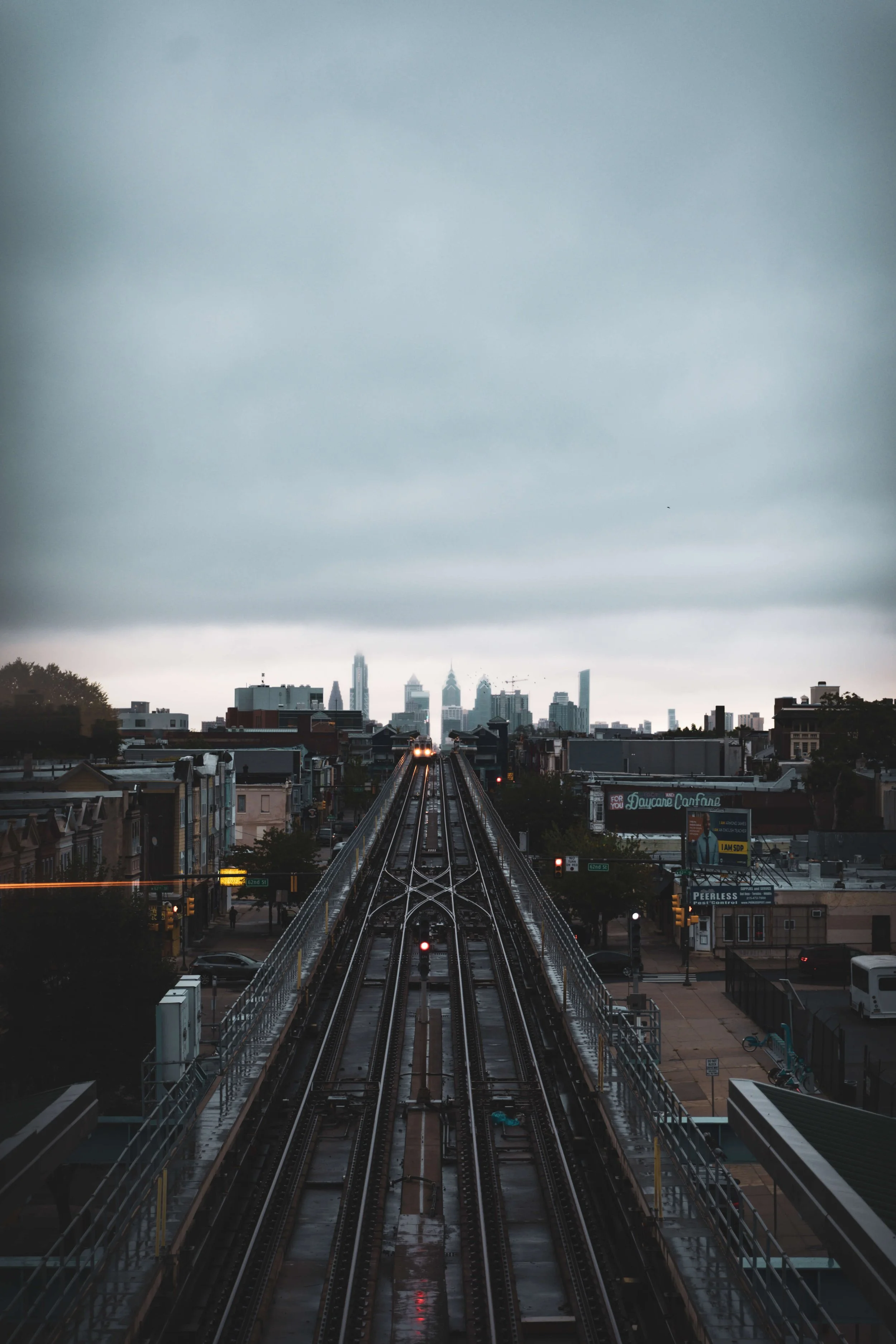 Urban train tracks leading into downtown skyscrapers on a cloudy day.