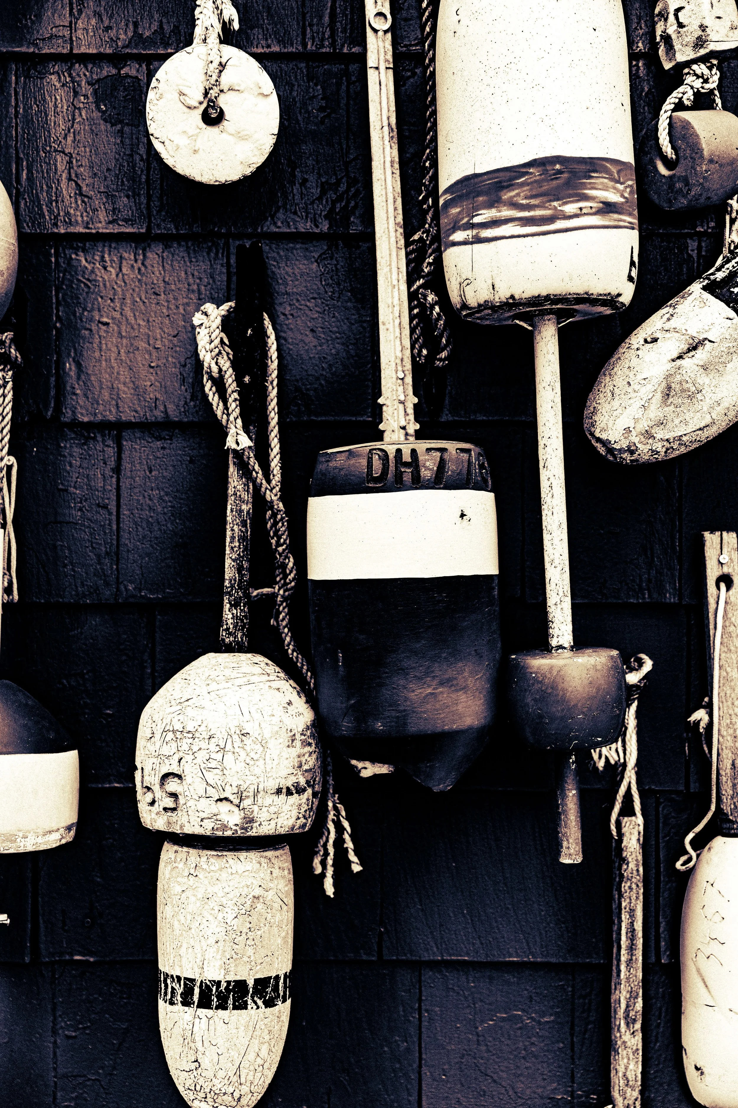 Various old nautical buoys and fishing floats hanging on a dark wall.