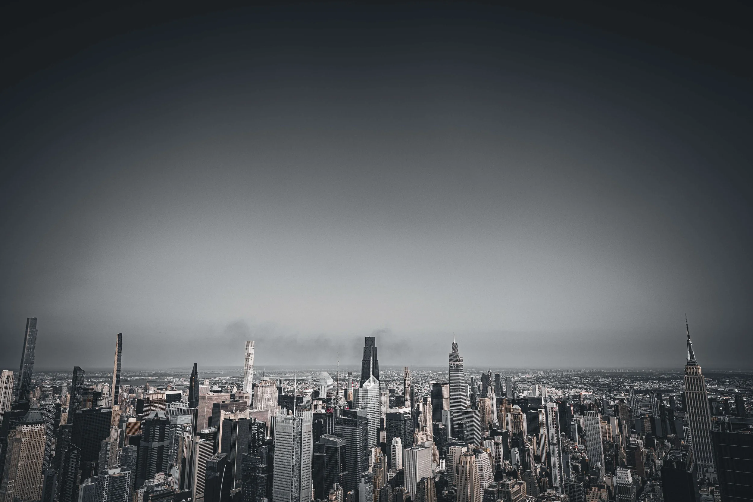 Black and white aerial view of a city skyline with tall skyscrapers and buildings.
