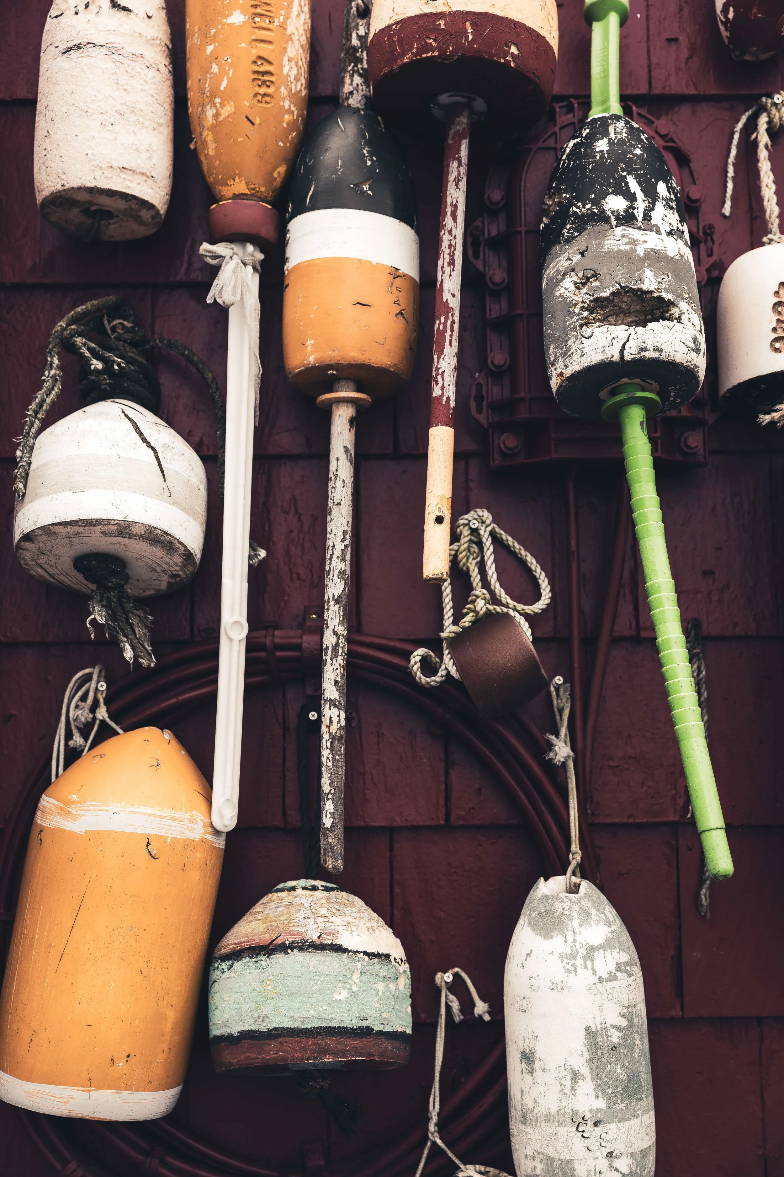 Collection of weathered fishing buoys hanging on a wall.