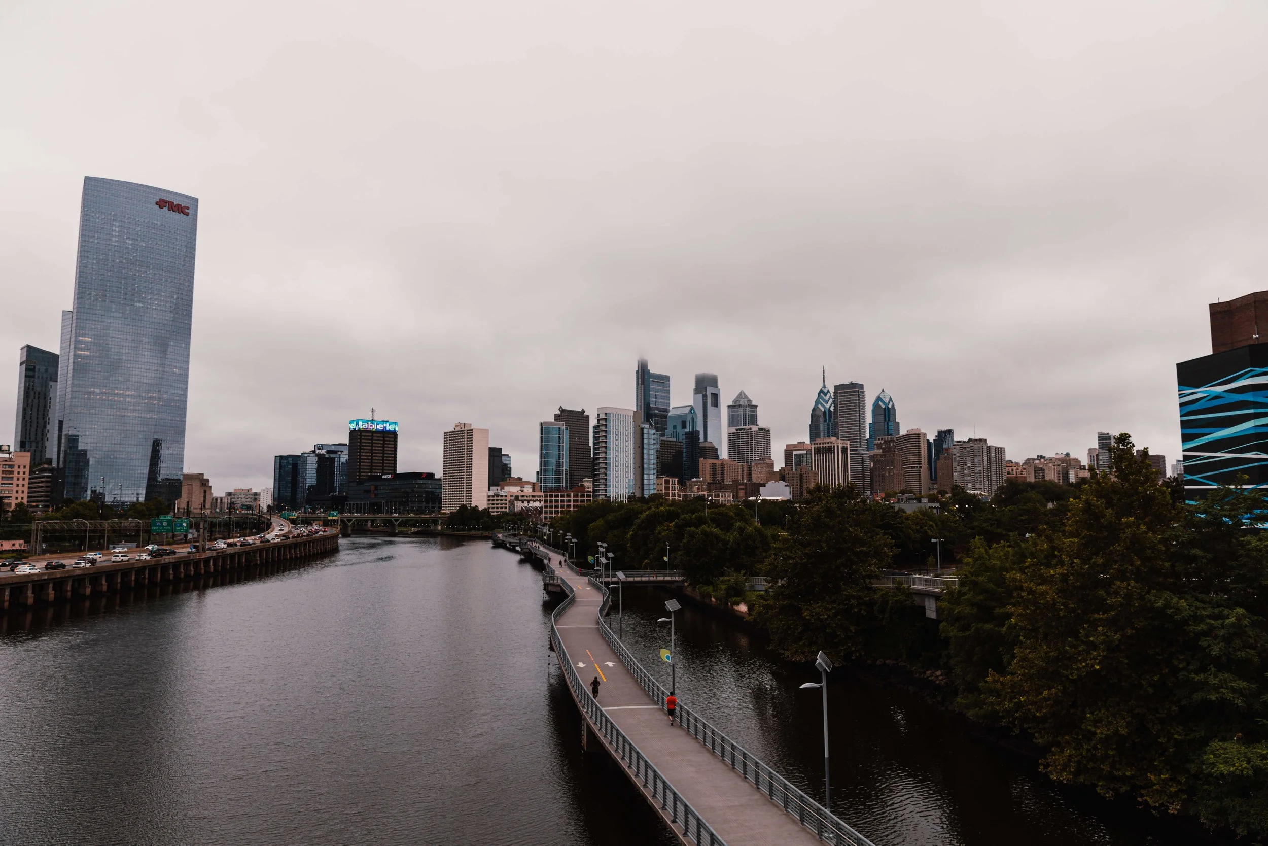 Overcast city skyline with a river and a pedestrian walkway in the foreground, downtown Philadelphia skyline, PA.