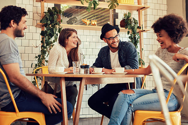 Four friends sitting at a table in a cozy cafe, laughing and talking.