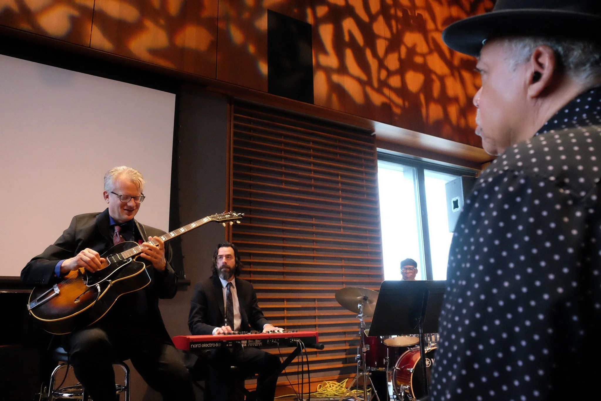 Blues man Billy Branch studying guitarist Mike Allemana, accompanied here by organist Pete Benson and drummer Linard Stroud. (Photograph by Lauren Deutsch)