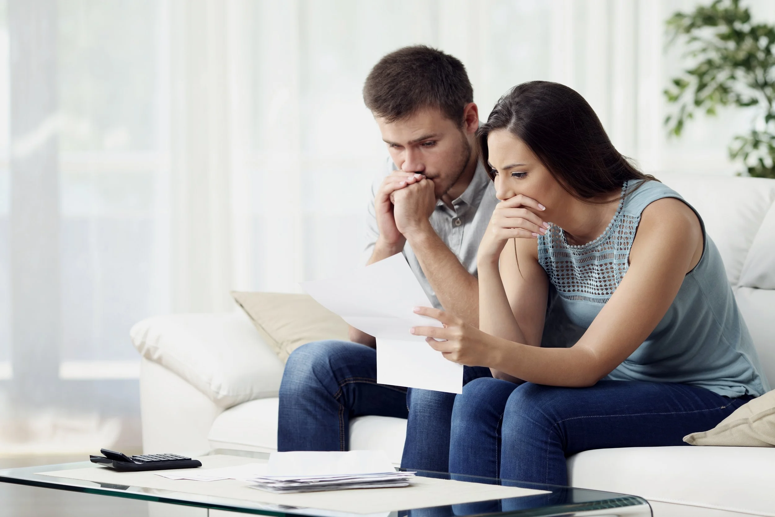 An  uncertain young couple looking at a financial document