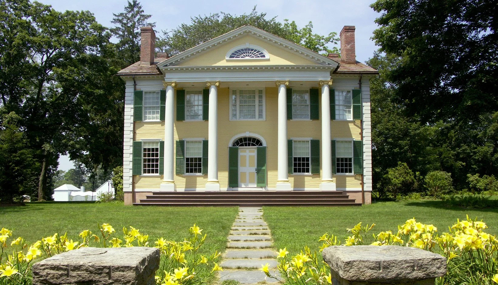 The Florence Griswold House. A yellow, two-story house with white columns and green shutters.