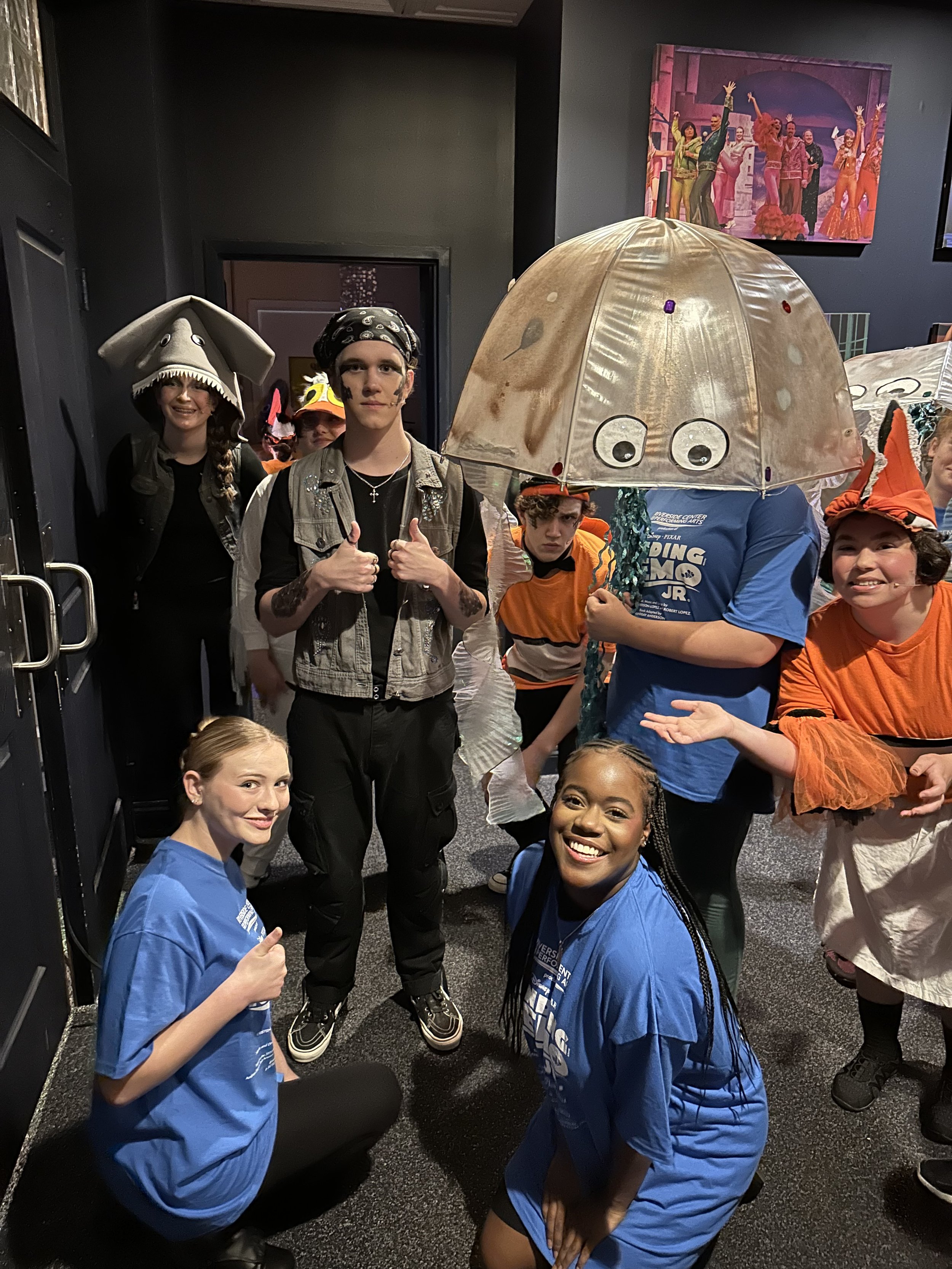 Sharks, jellyfish, and crew preparing for their performance of Finding Nemo Jr. backstage.