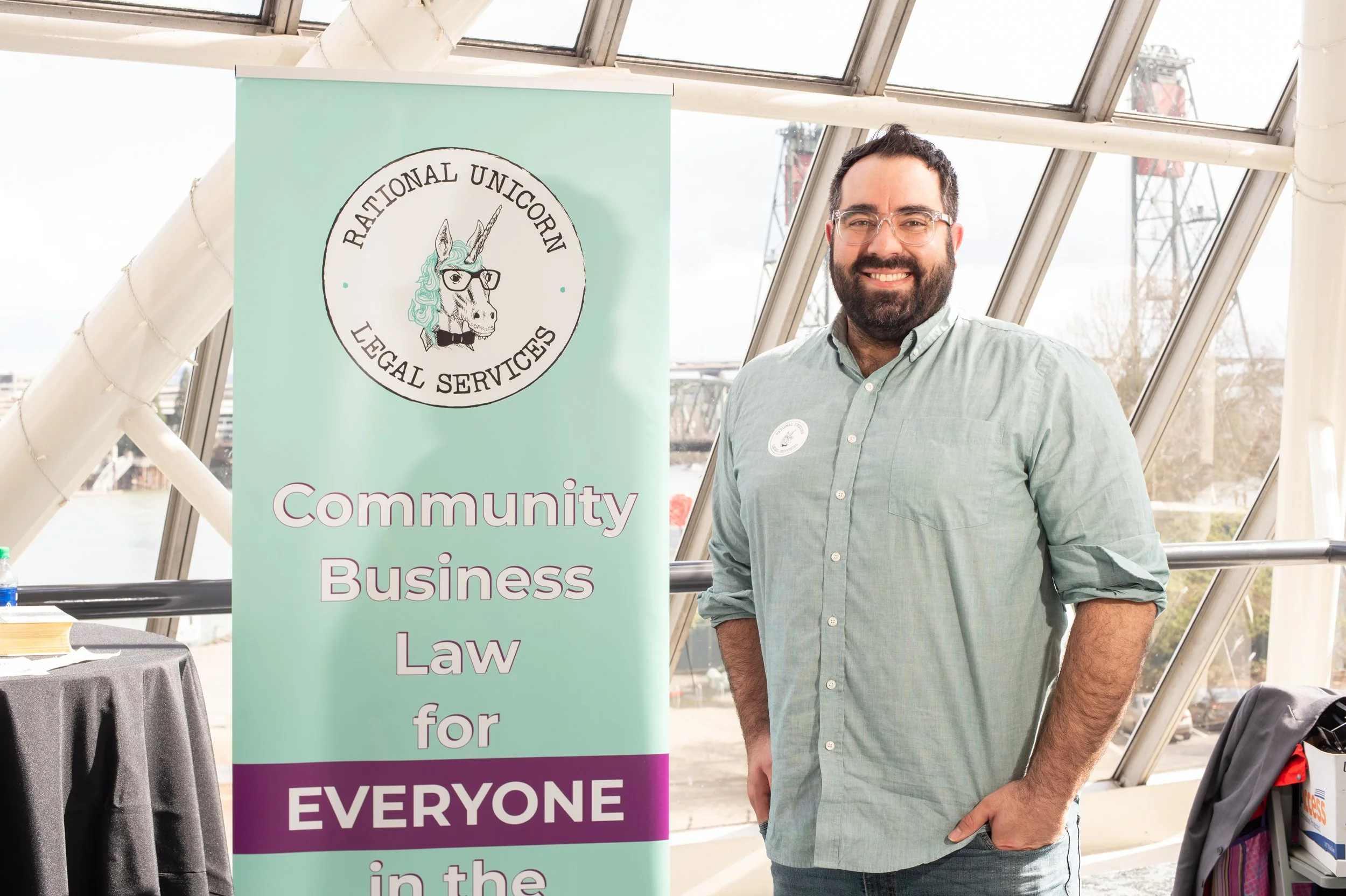 Michael Jonas standing in front of a Rational Unicorn Legal Services banner at a business conference.