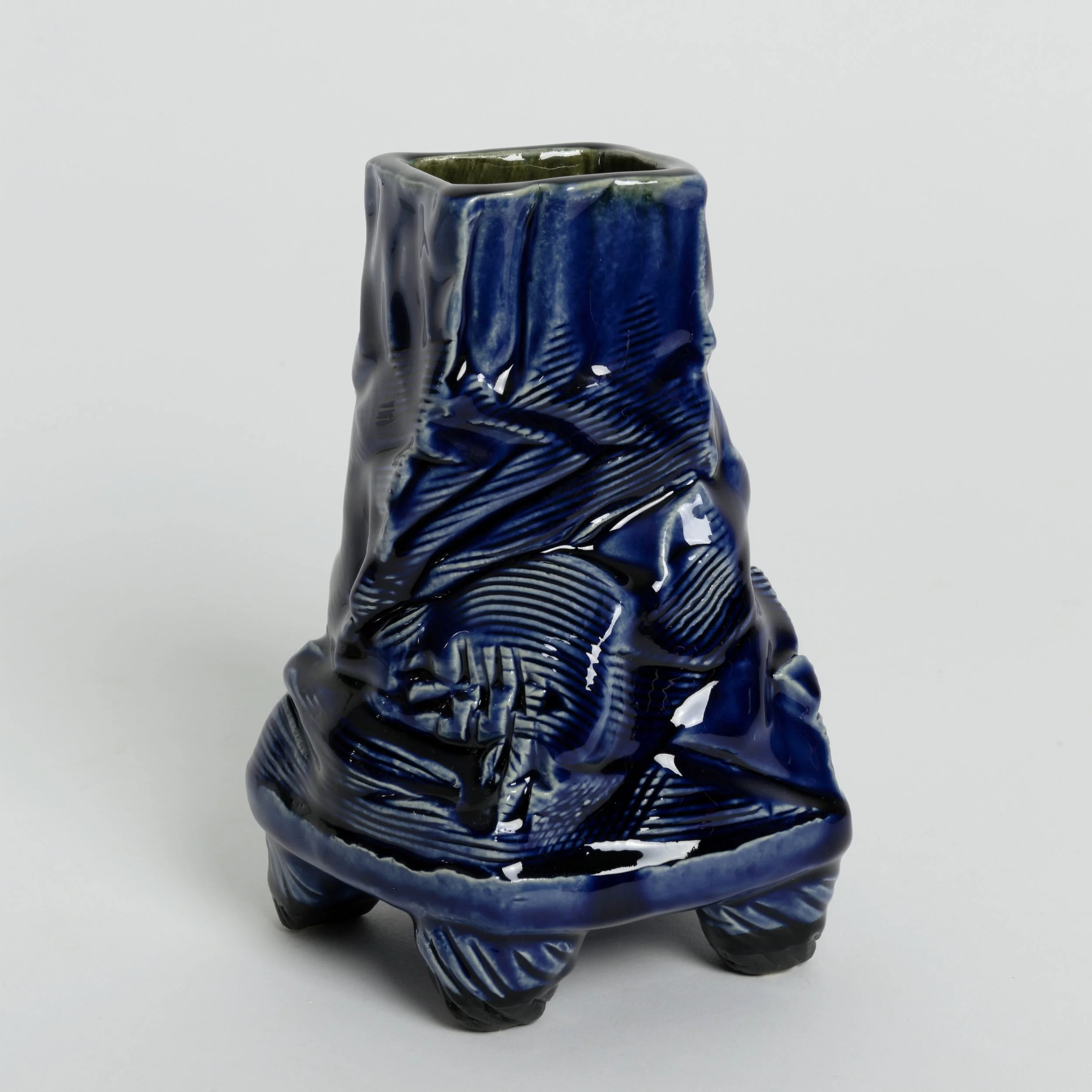 Hand-built ceramic vessel with four feet, square tapered form, rhythmic surface texture, with cobalt and black gloss glazes